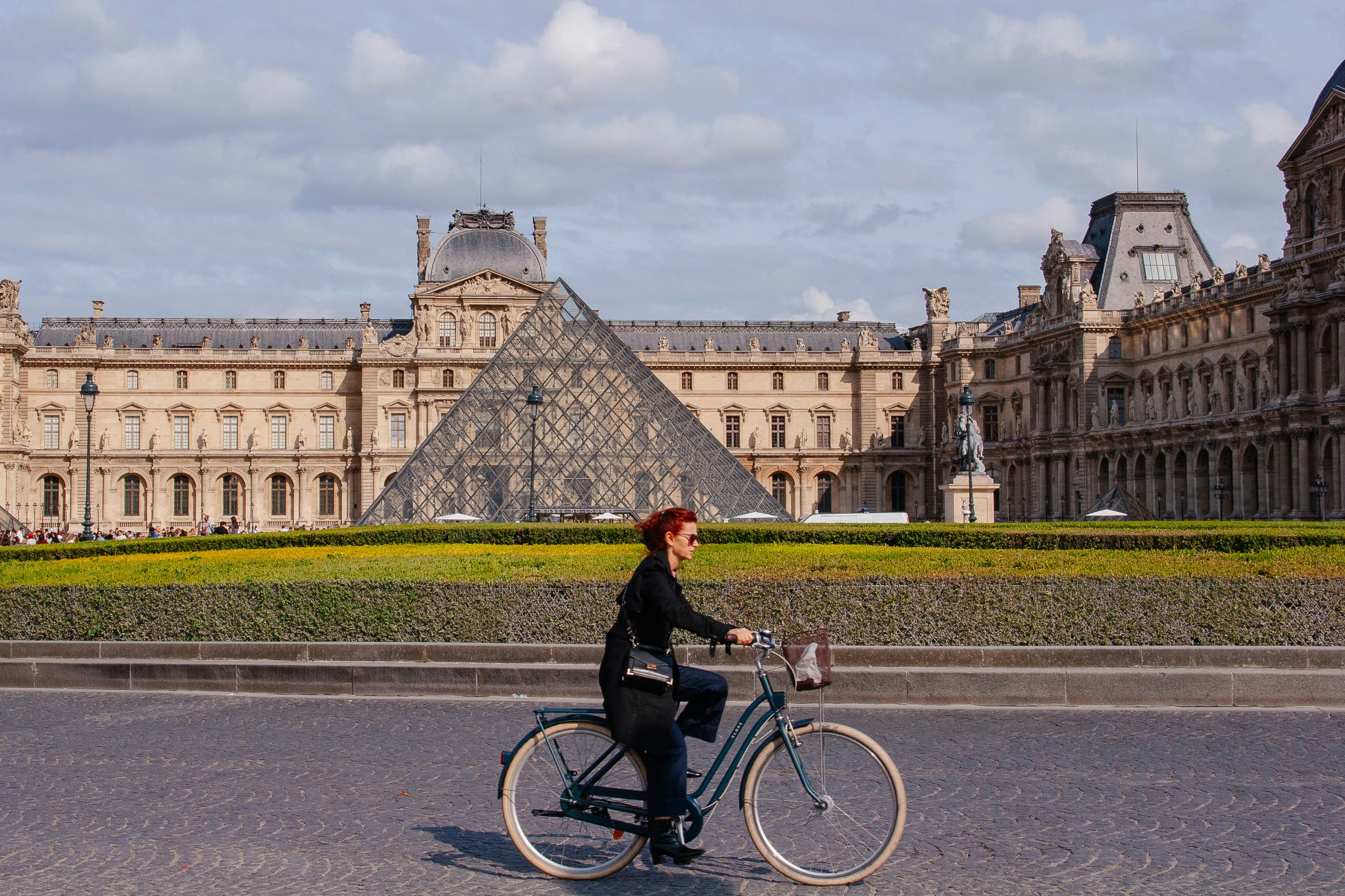Woman cycling past the louvre pyramid in paris