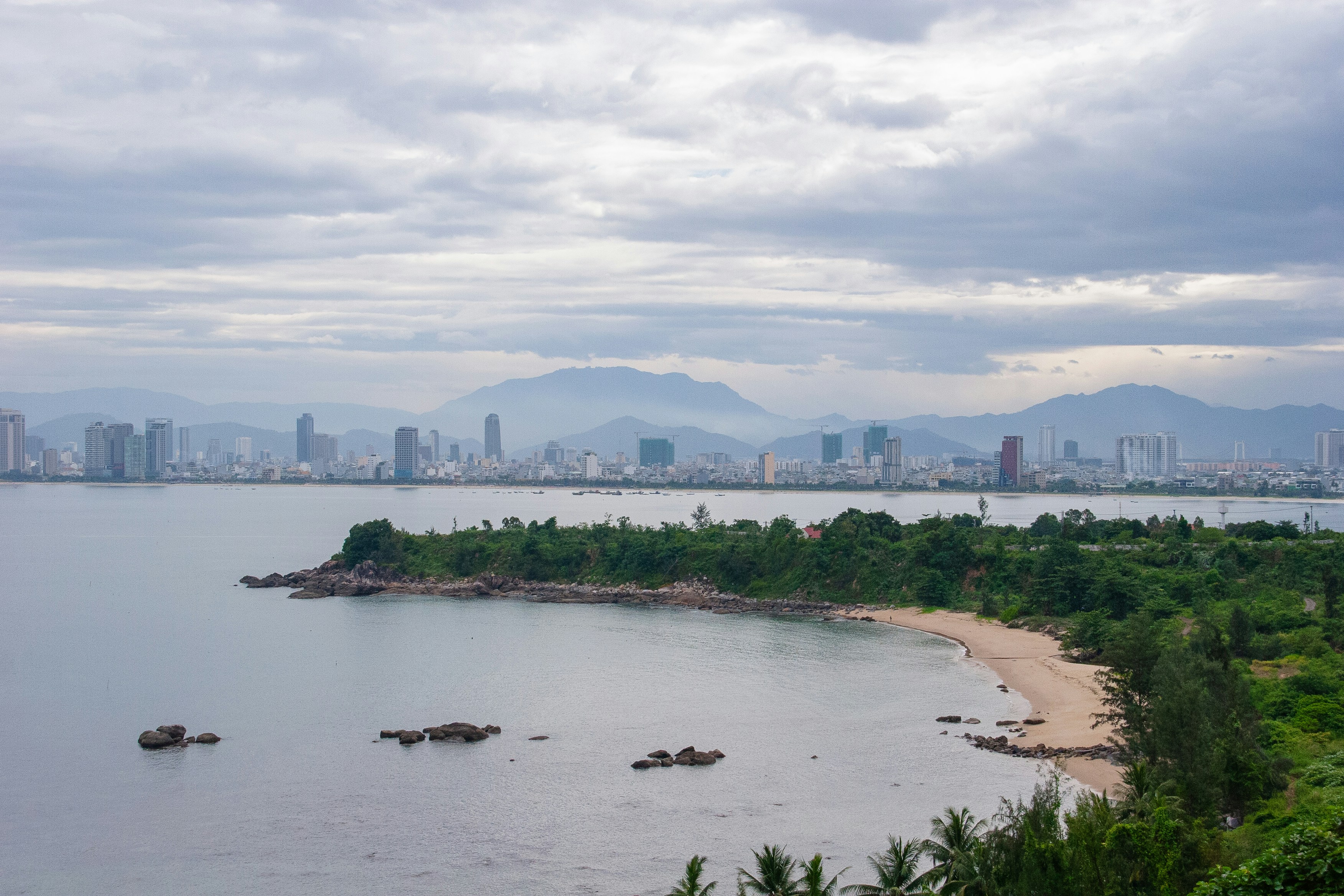 Coastal city skyline with mountains in the background.