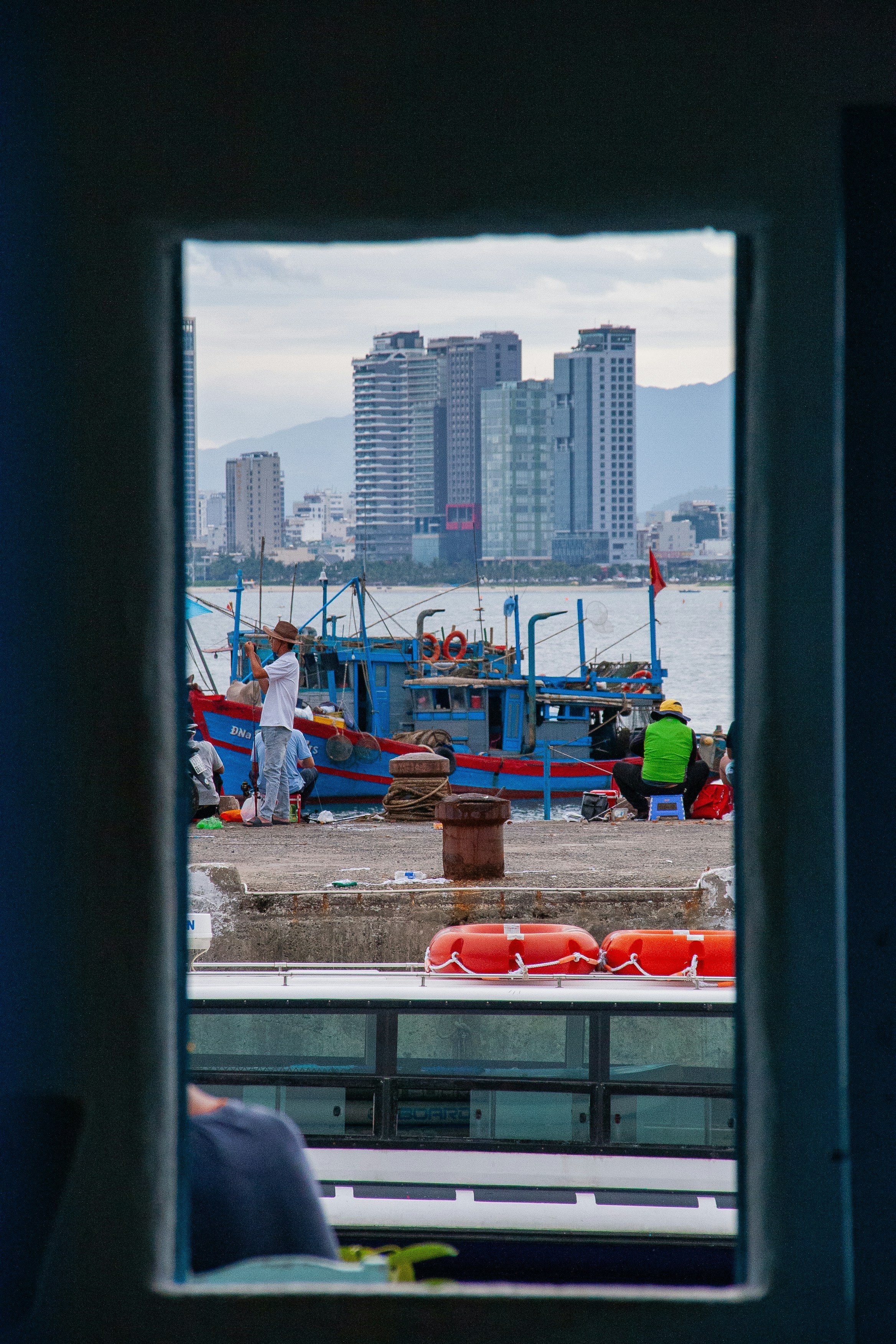 Boats docked at a pier with city skyline in background.