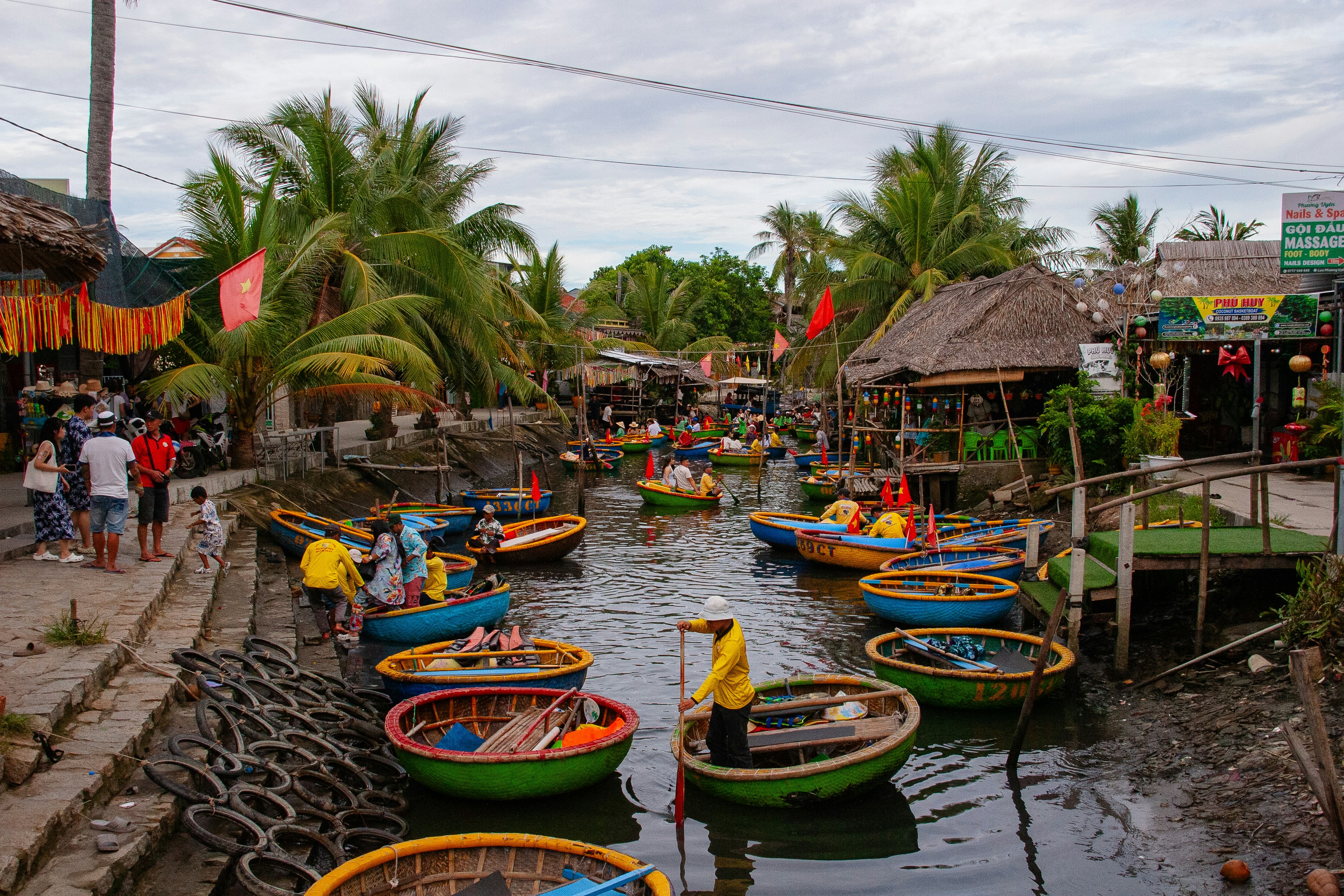 Round boats in a canal with palm trees and buildings.