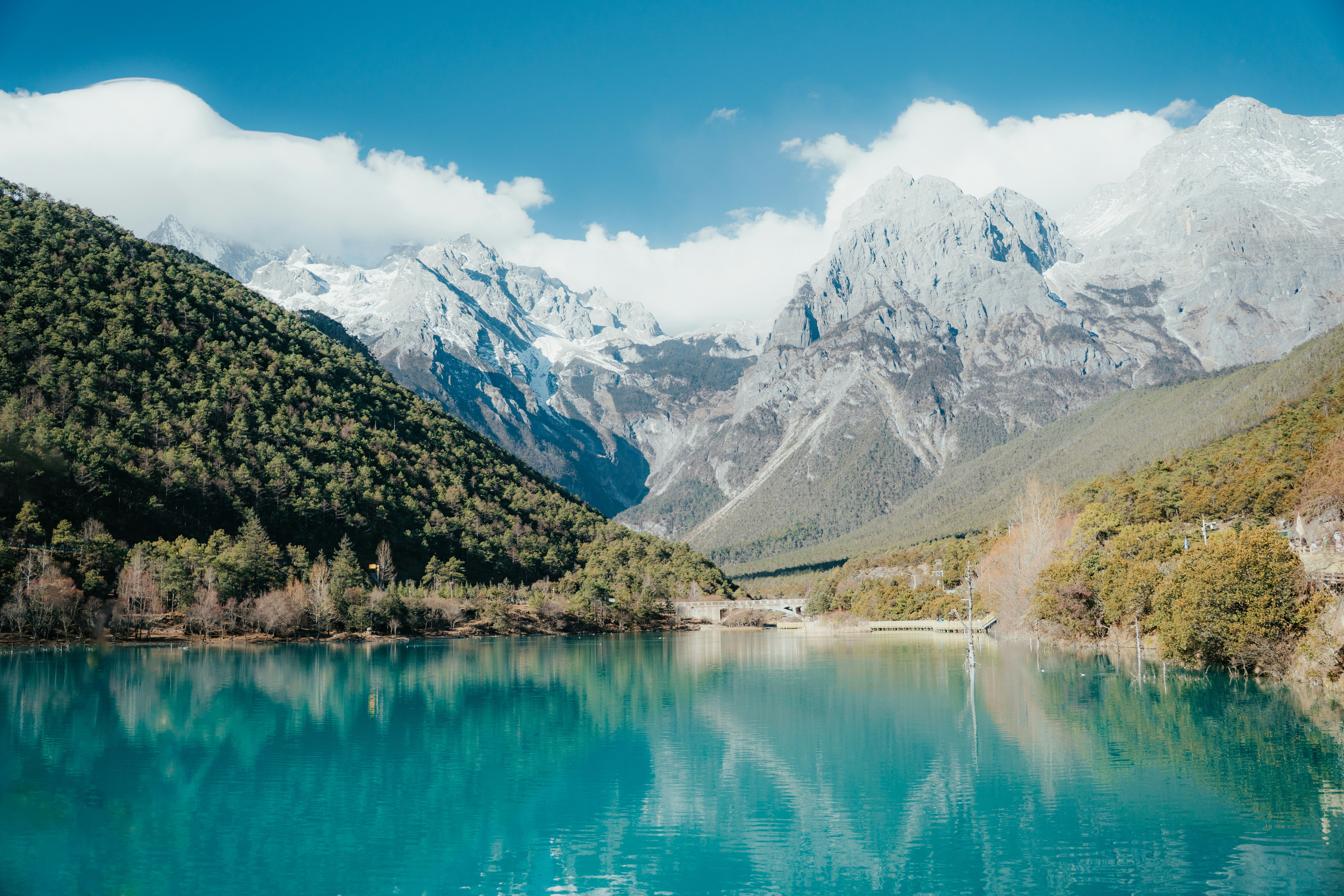 El lago turquesa refleja majestuosas montañas nevadas y bosques verdes.