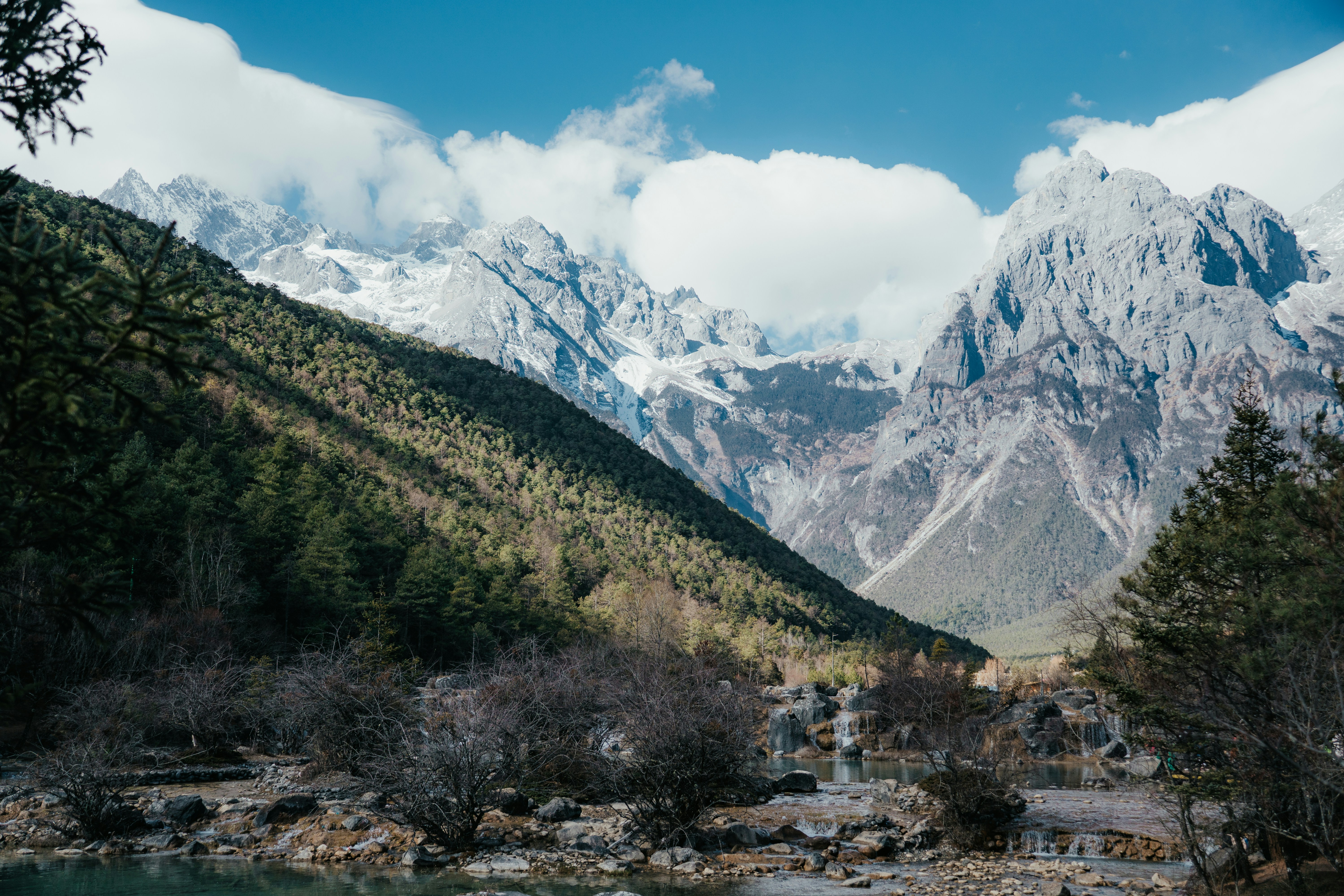 Montañas nevadas bajo un cielo azul con nubes.