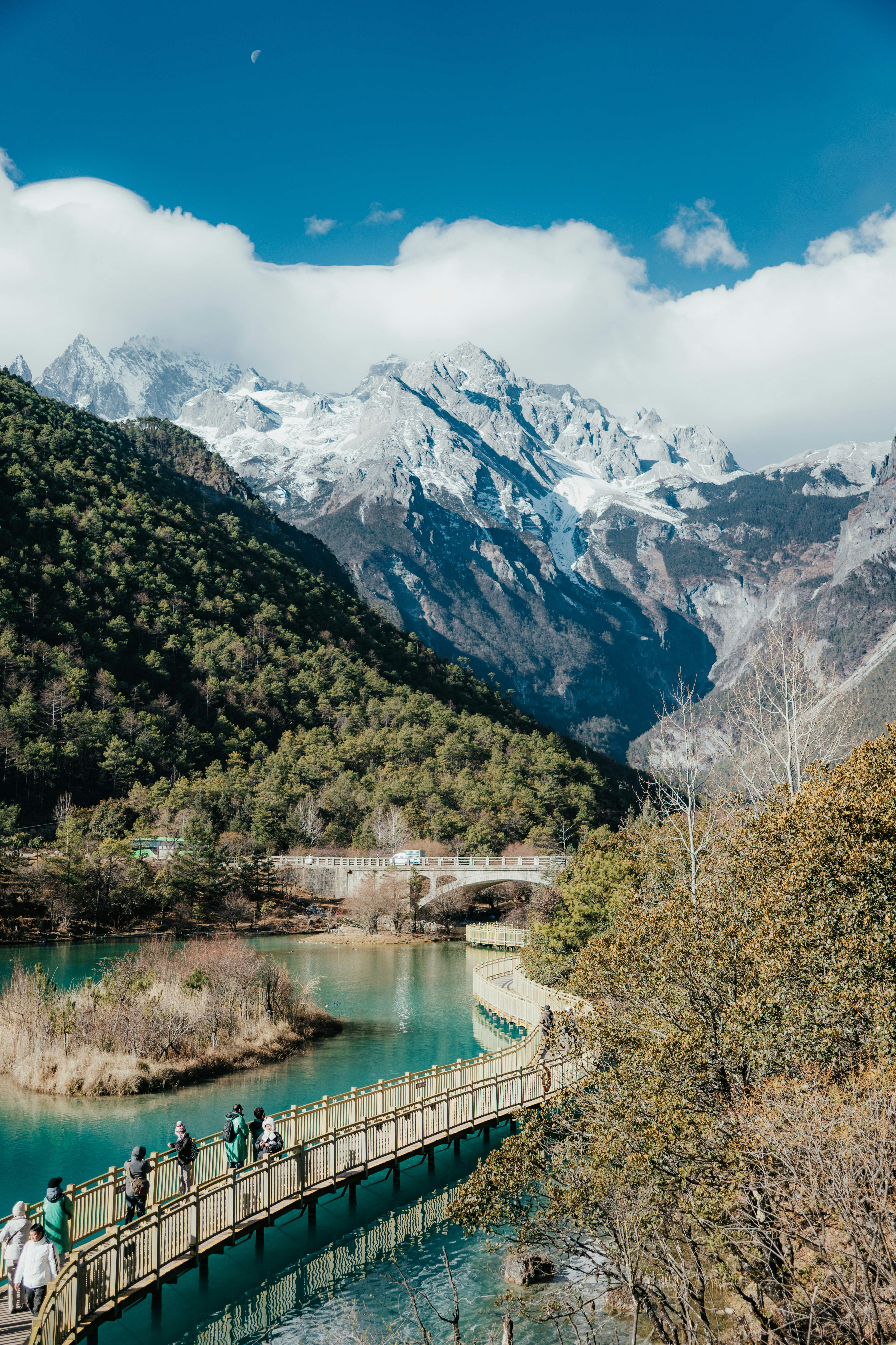 Puente de madera sobre aguas turquesas con montañas nevadas