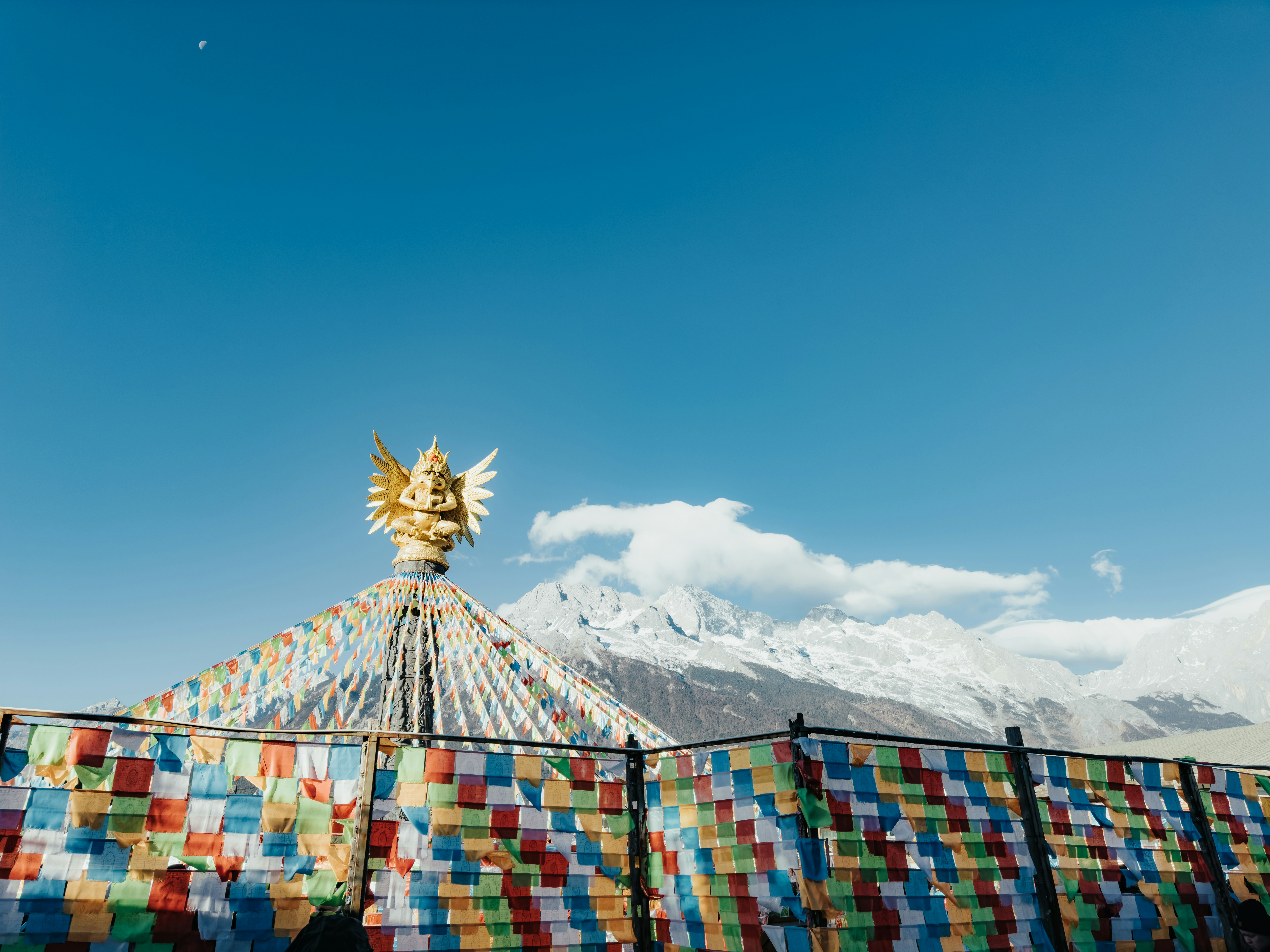 Estupa dorada con banderas de oración y montañas nevadas