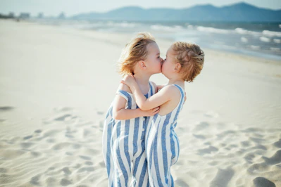 Two young children sharing a kiss on the beach