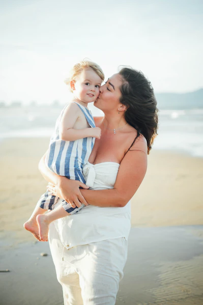 Mother kissing her child on the beach