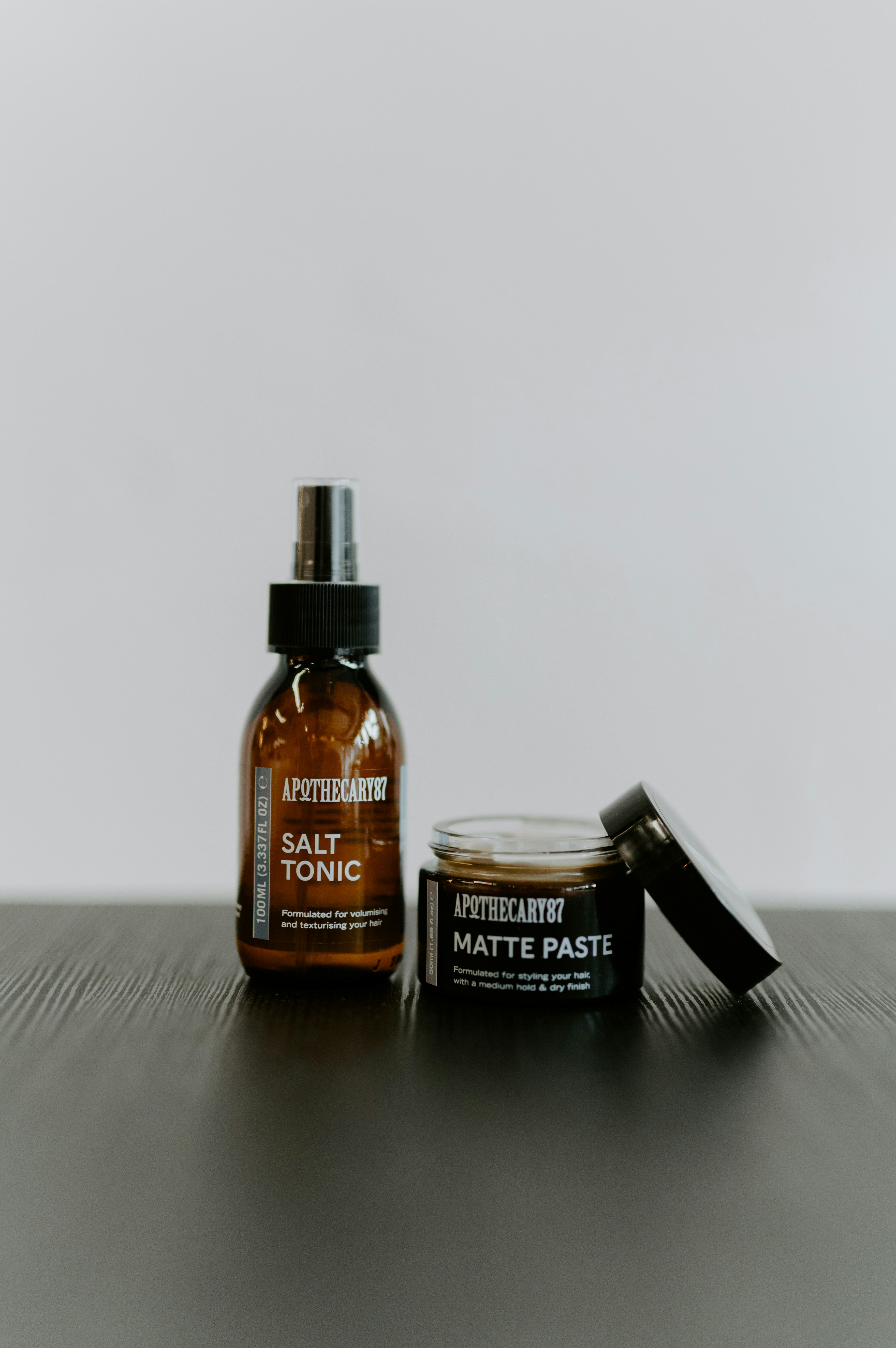 Two apothecary hair products on a dark surface.