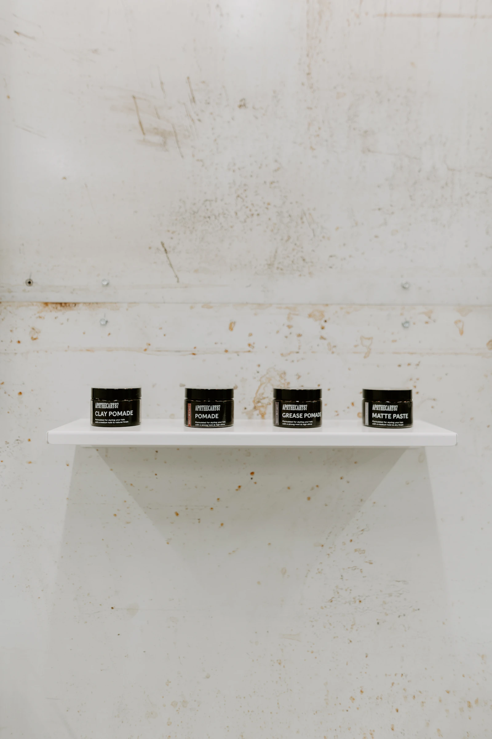 Four black premium skincare jars displayed on a white shelf, representing a clinic-brand comparison