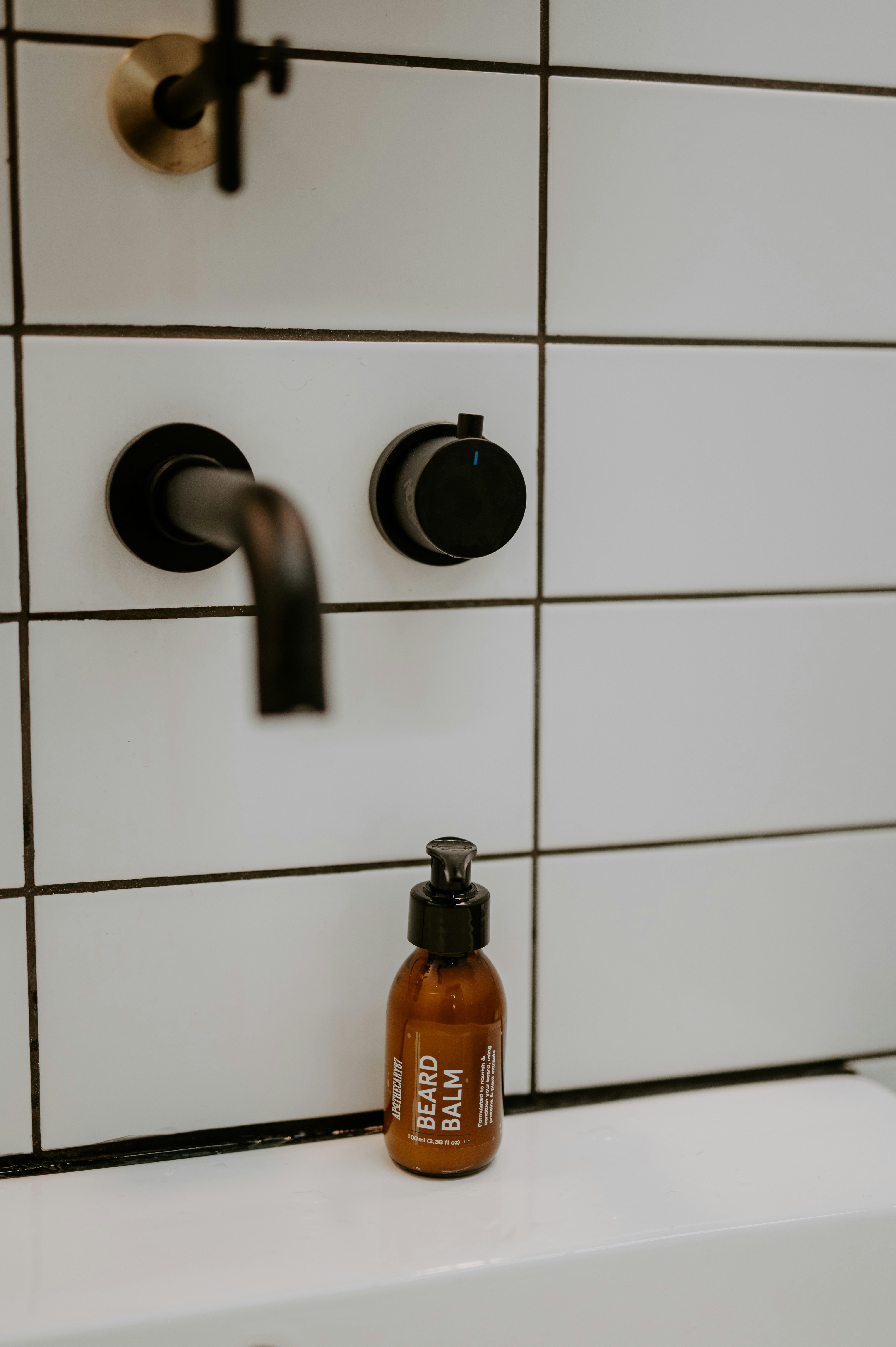 Beard balm bottle by a modern bathroom faucet