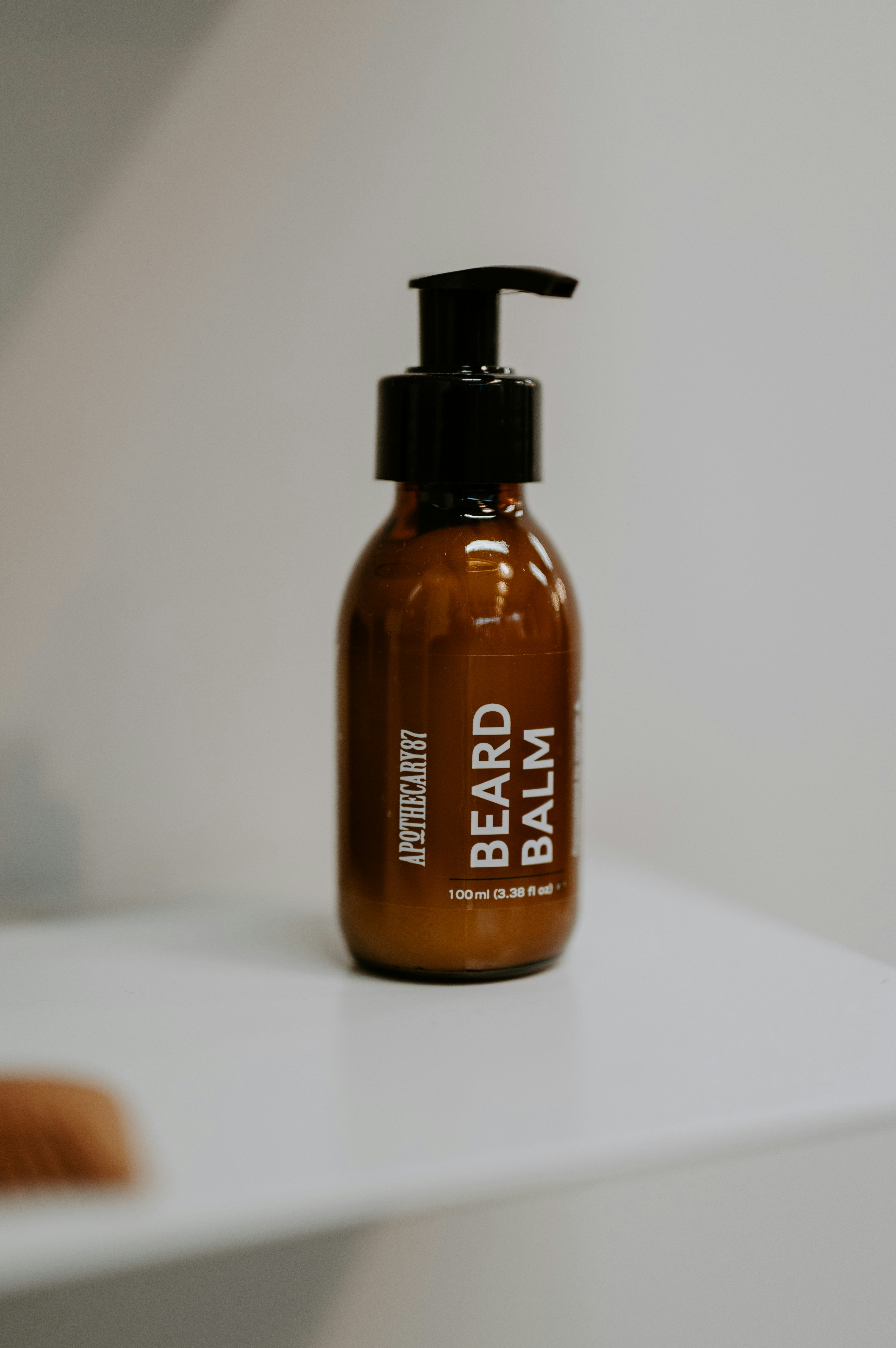 Brown bottle of beard balm with black pump dispenser.