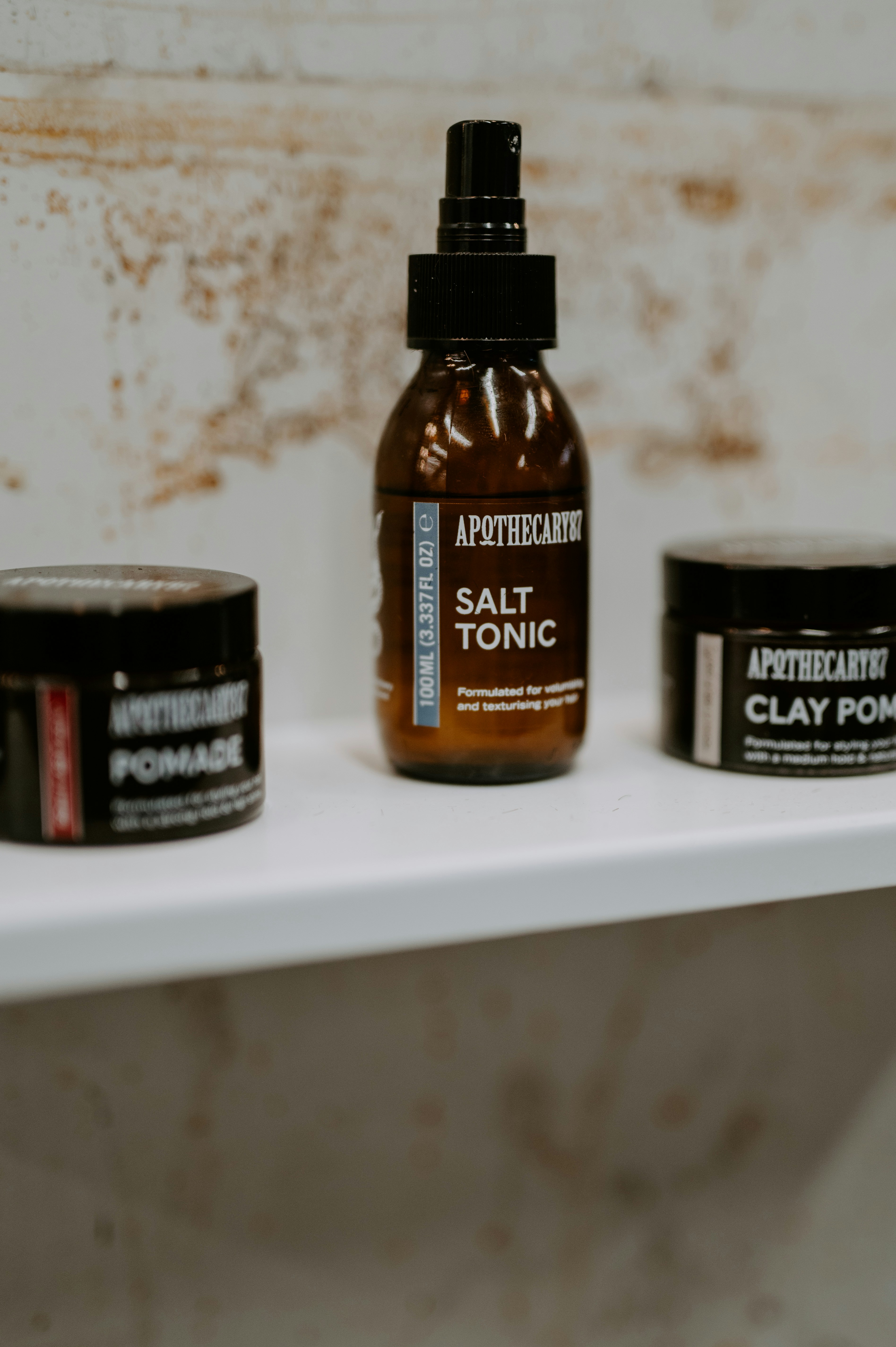 Three apothecary hair products on a shelf.
