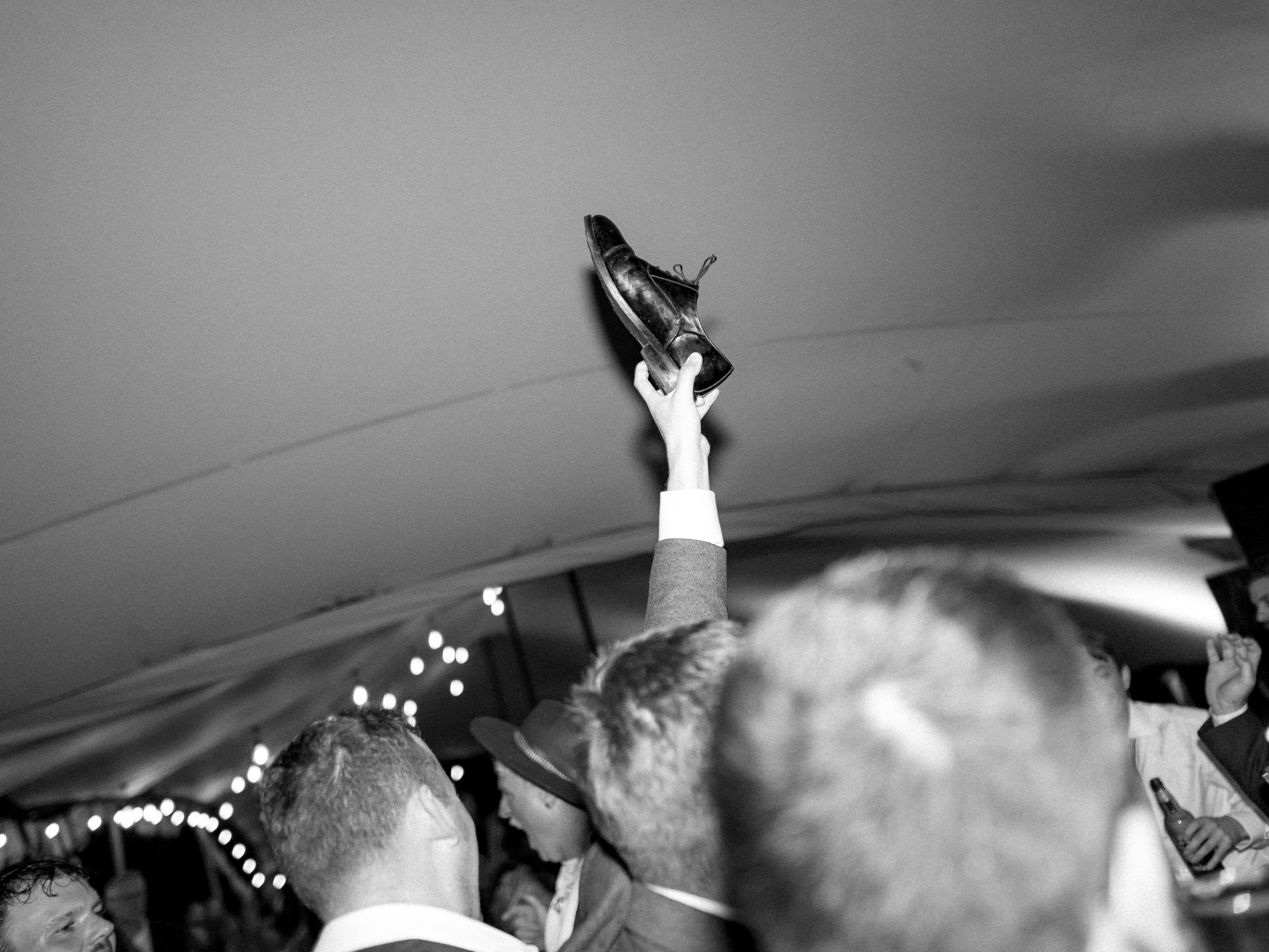 Man holds up shoe at a crowded event