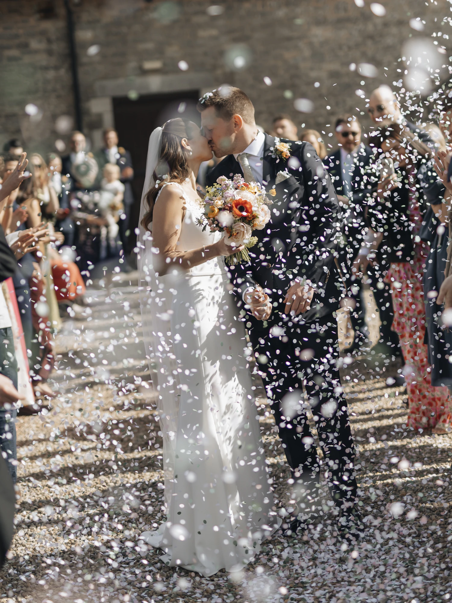 Confetti thrown over a couple walking out between two rows of guests