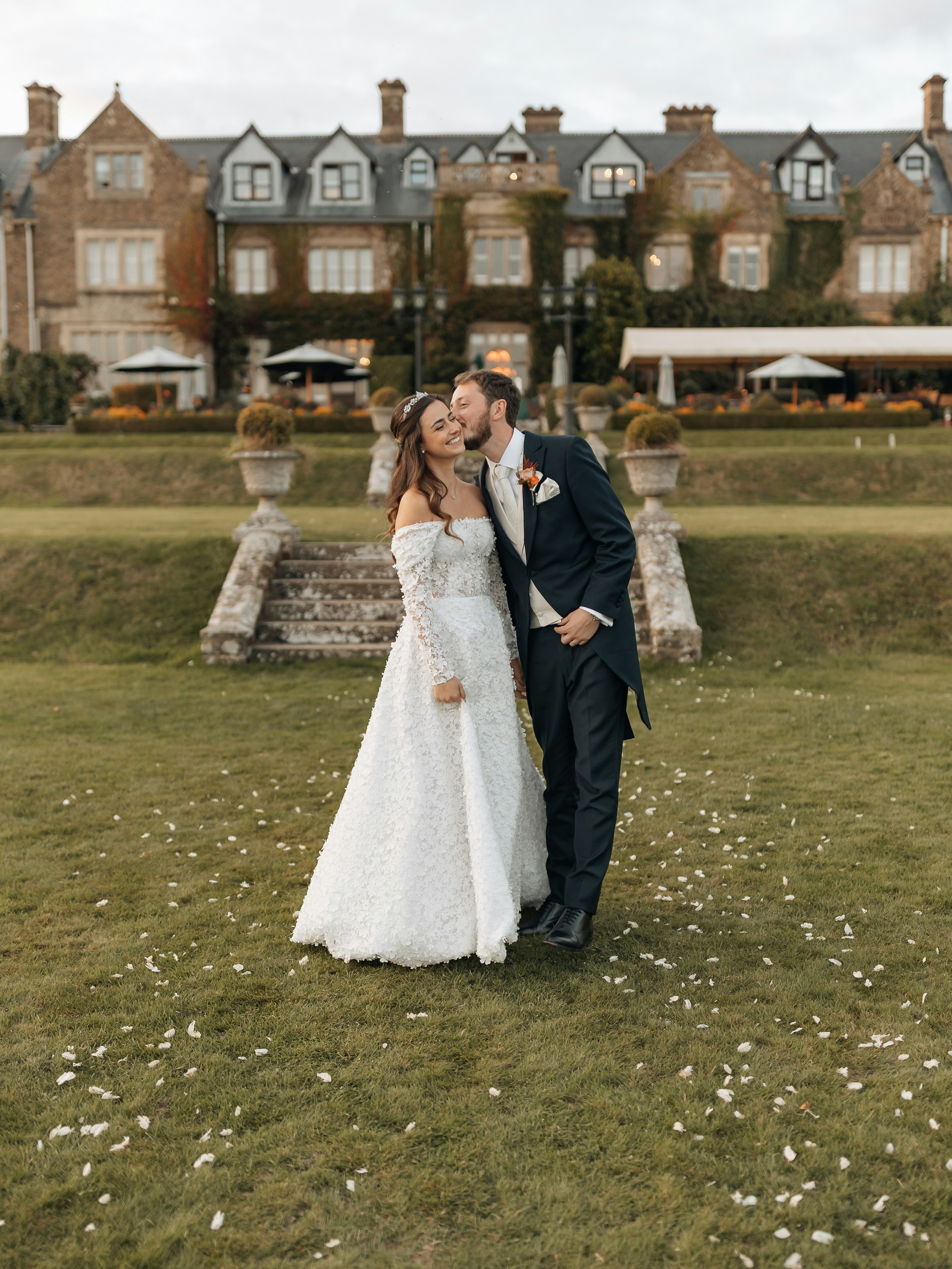 Bride and groom sharing a kiss outside a grand estate
