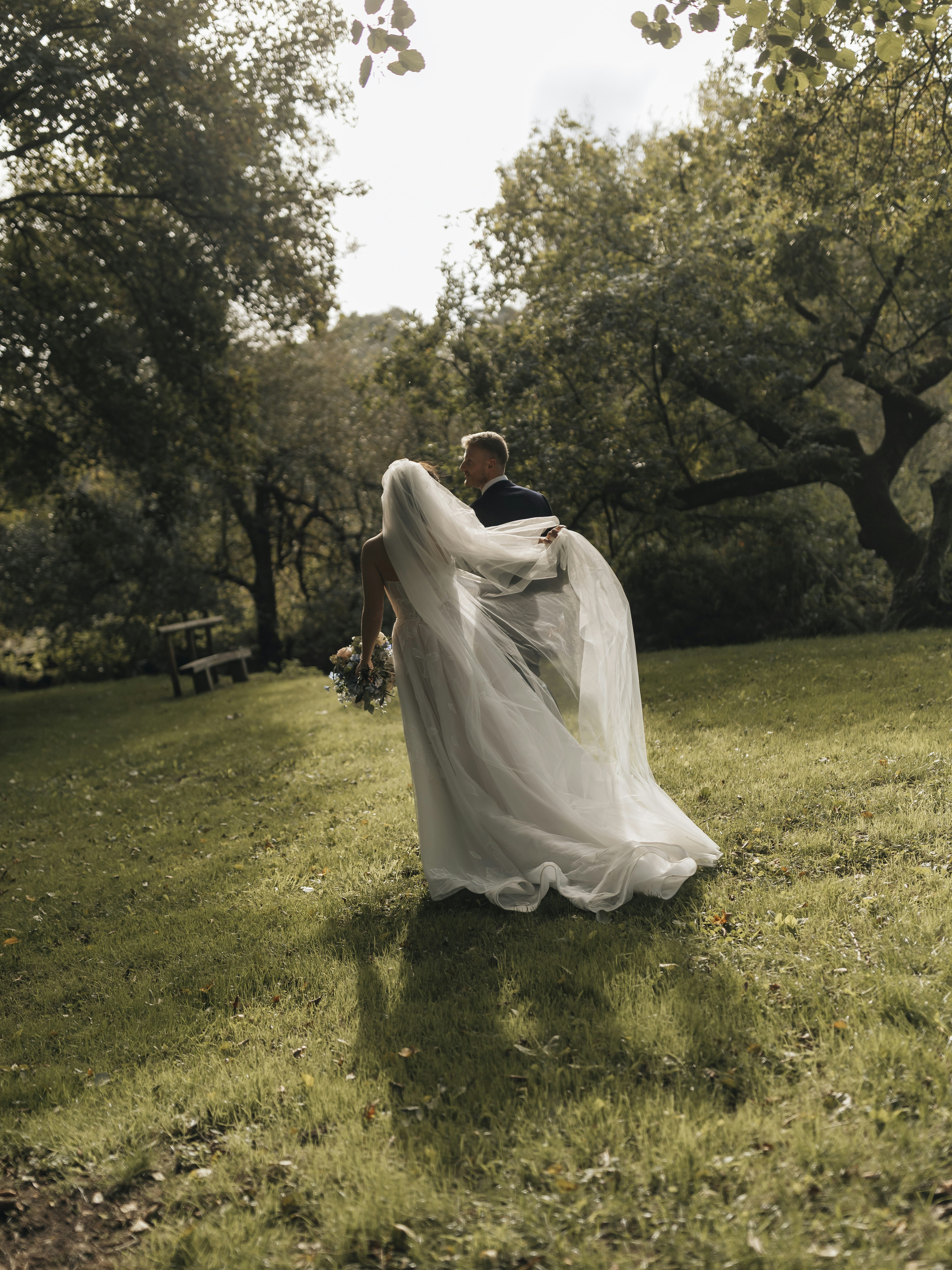 Bride and groom walking in a grassy park