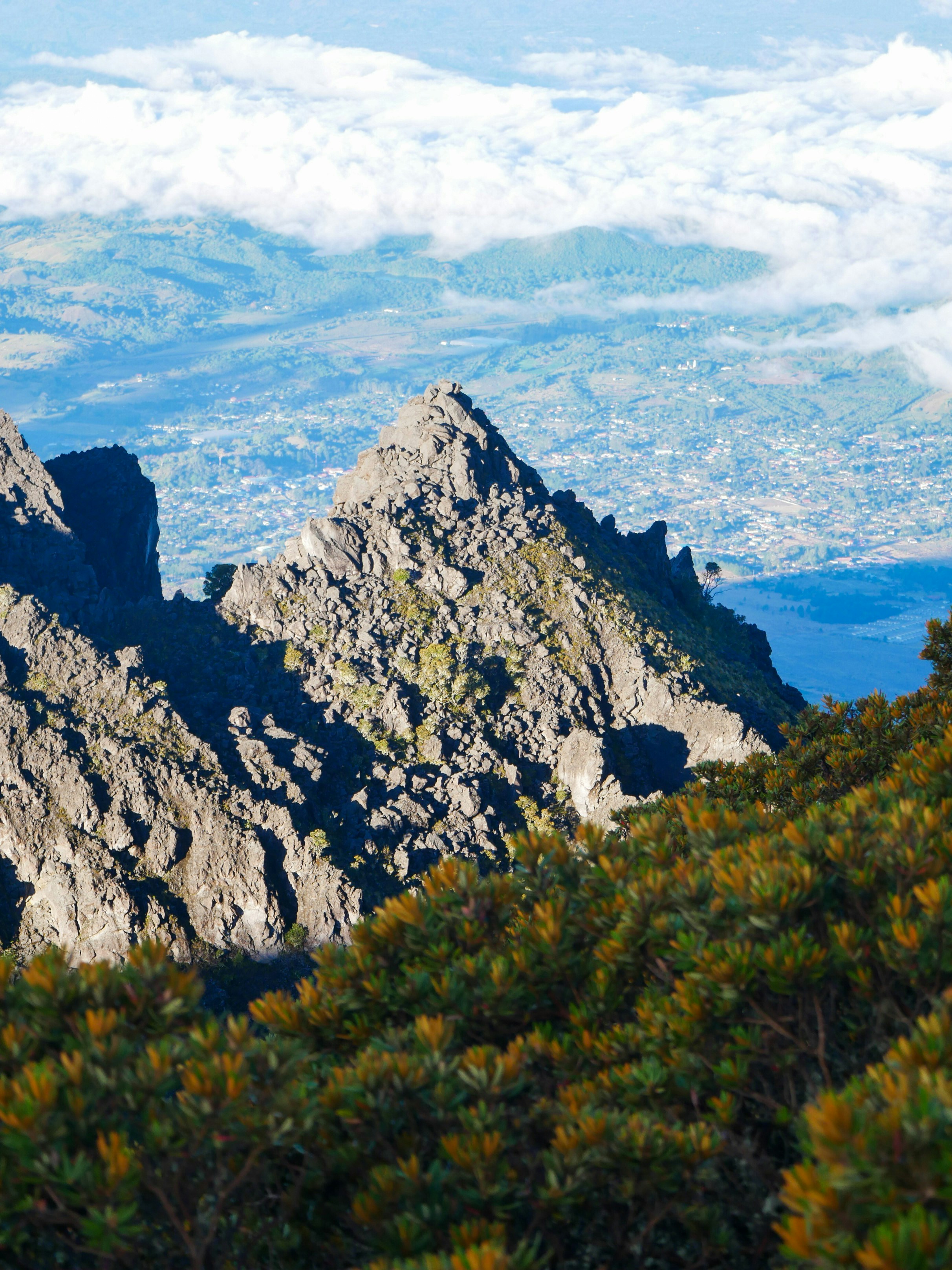 Puncak gunung bergerigi di atas lembah berawan