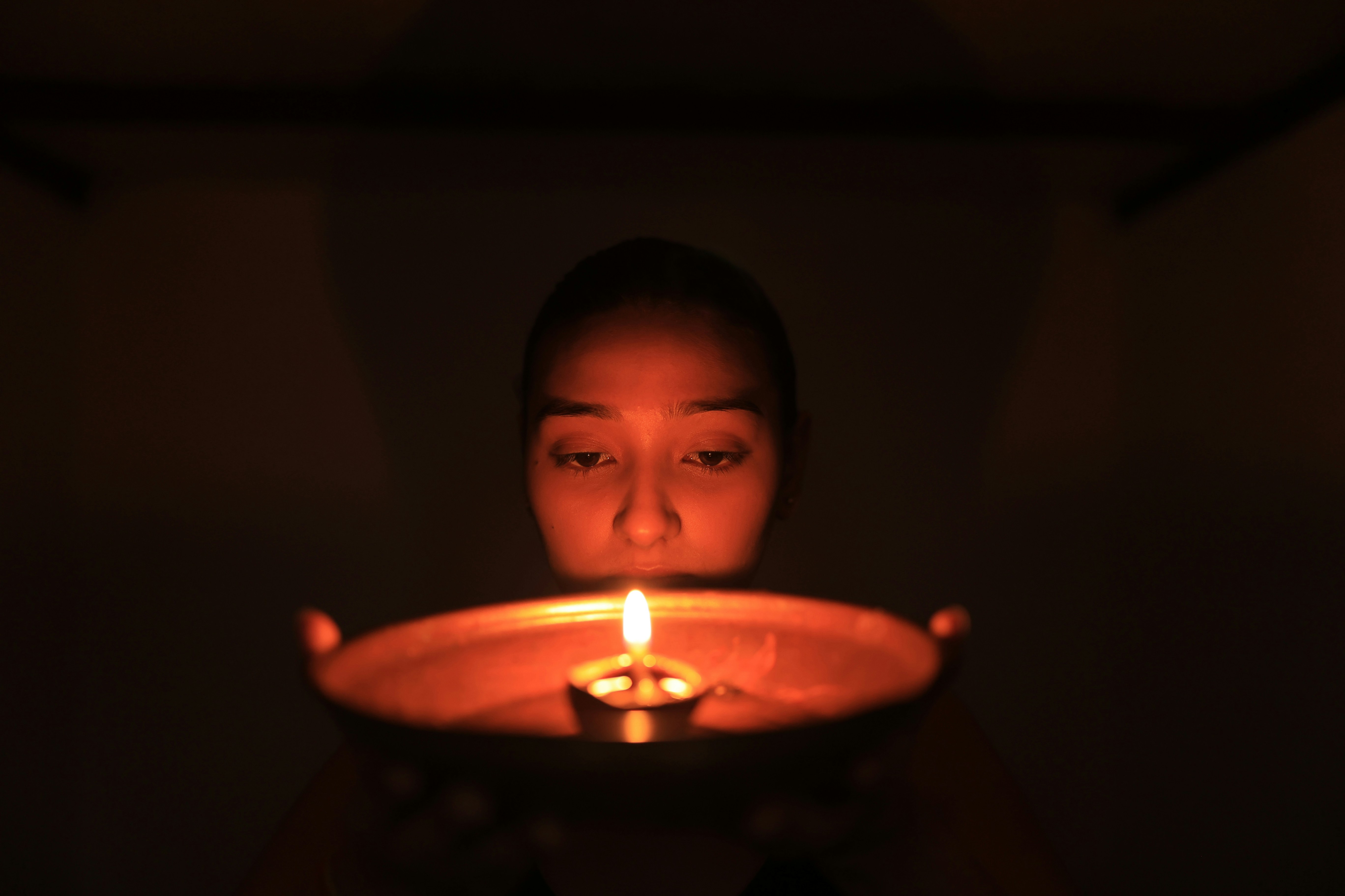 Woman holding a lit oil lamp in darkness
