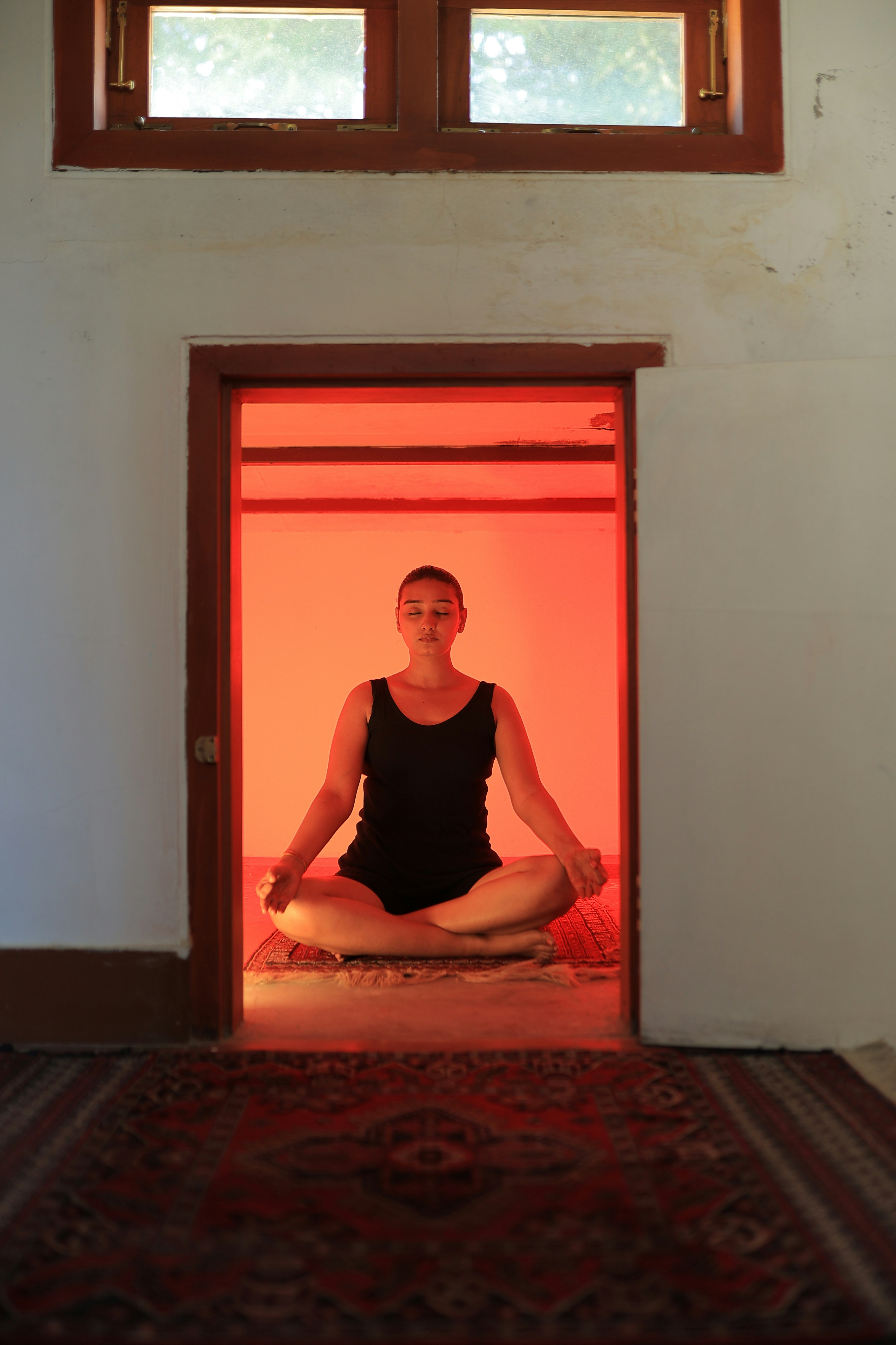 Woman meditating in a brightly lit red room.