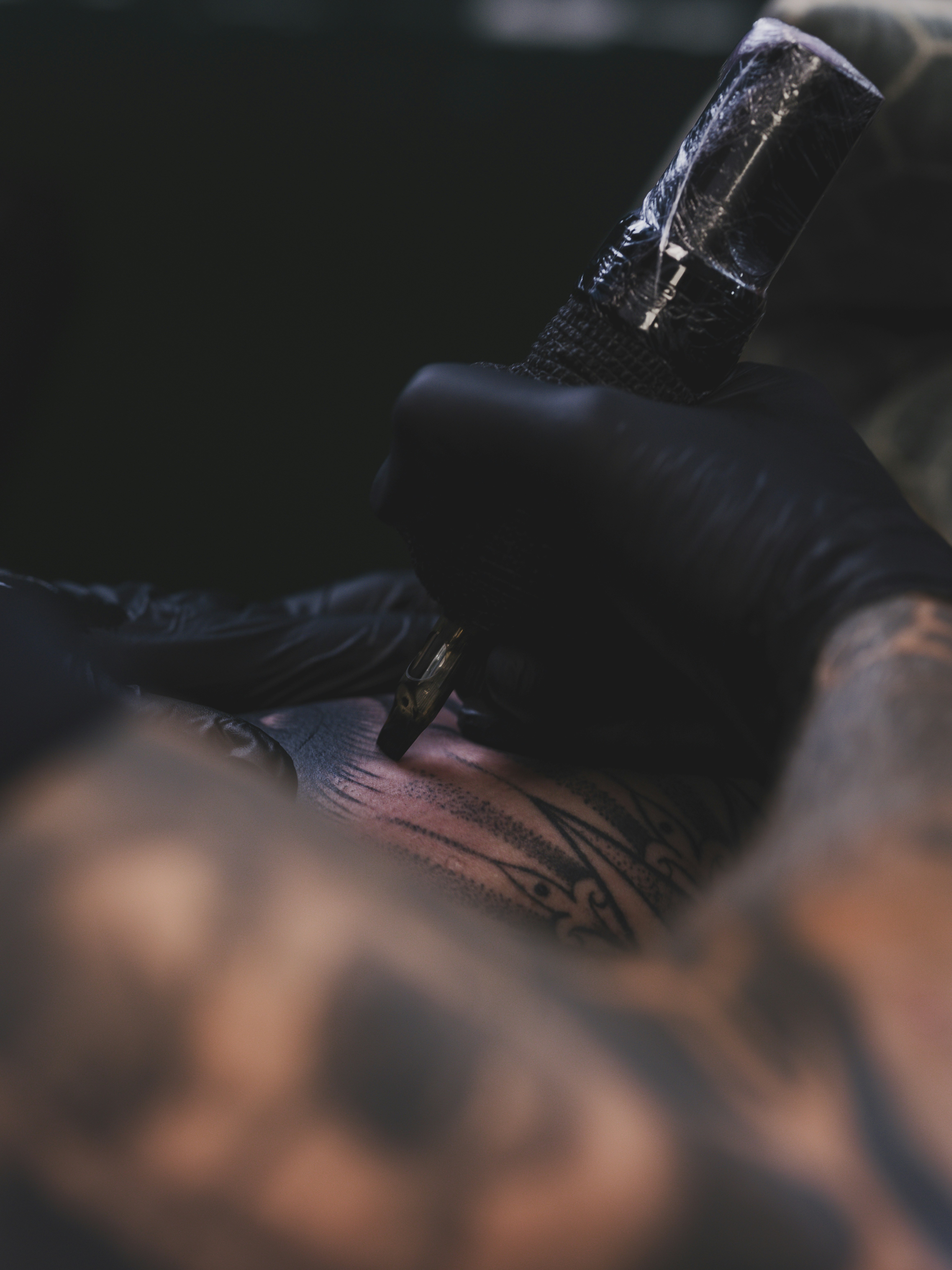 Tatuador trabalhando na pele de um cliente