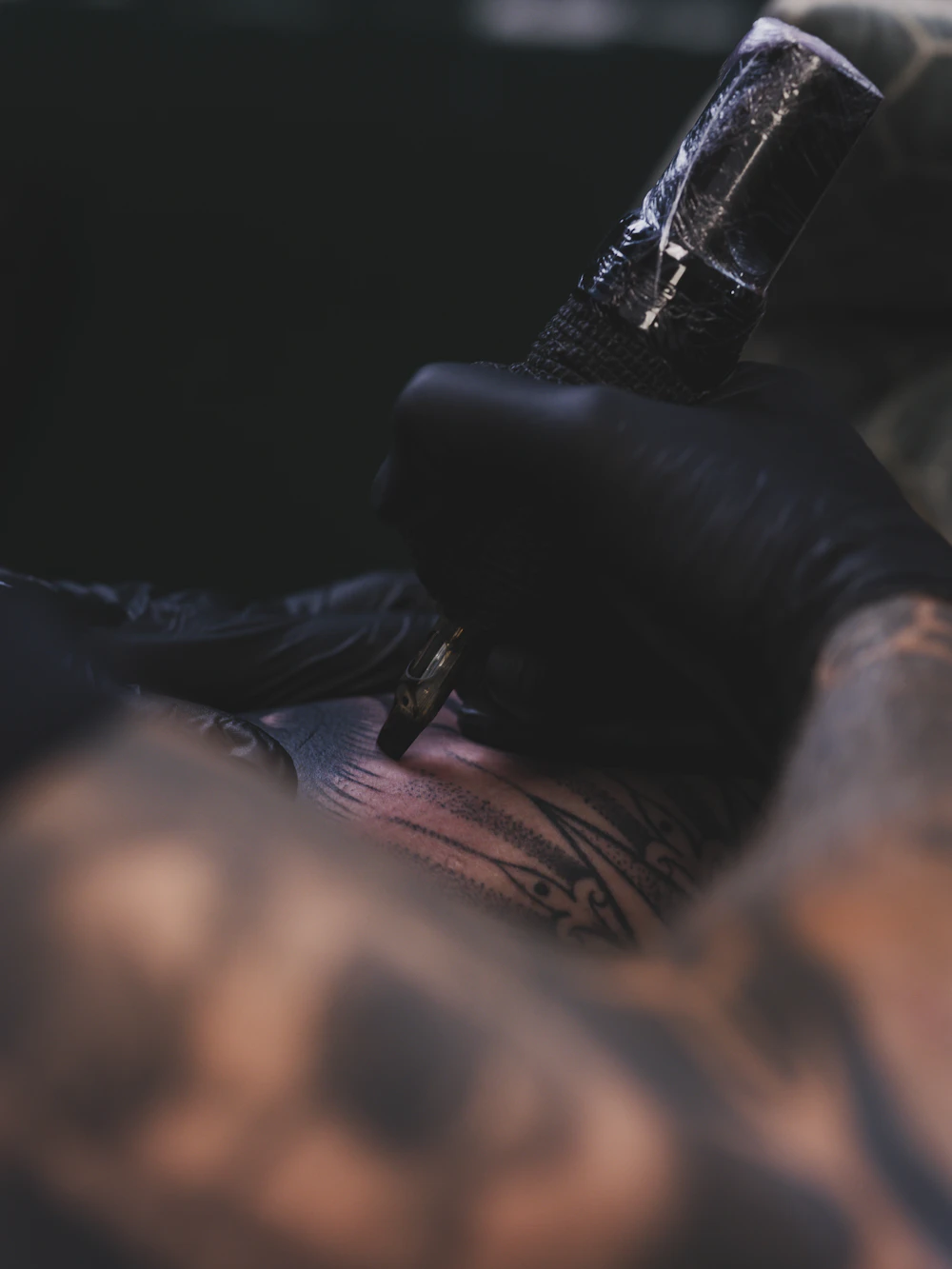 Tatuador aplicando tinta no braço de um cliente