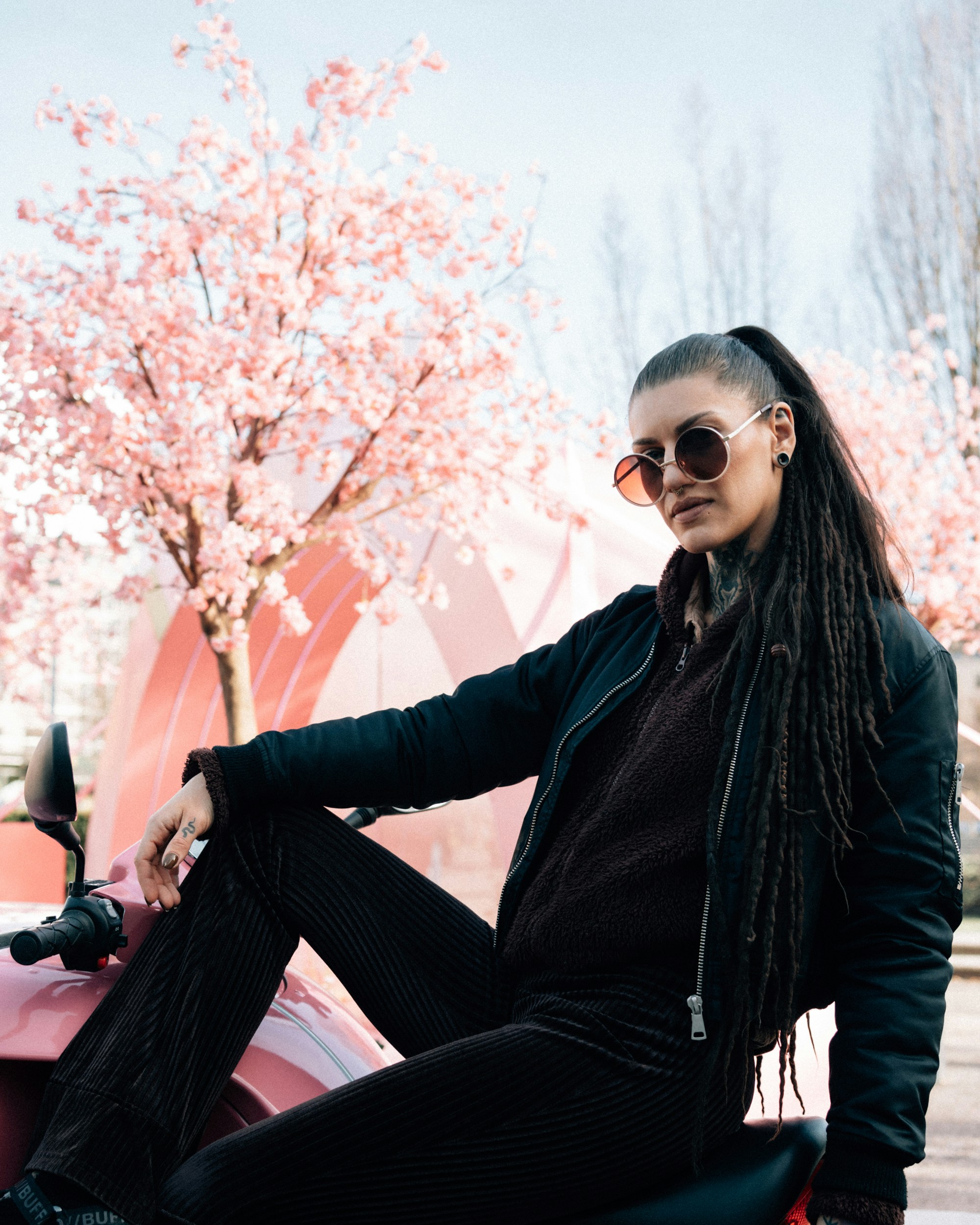 Woman posing on a pink scooter with cherry blossoms