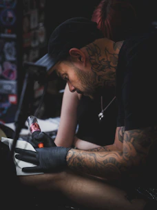 Tattoo artist working on client's arm