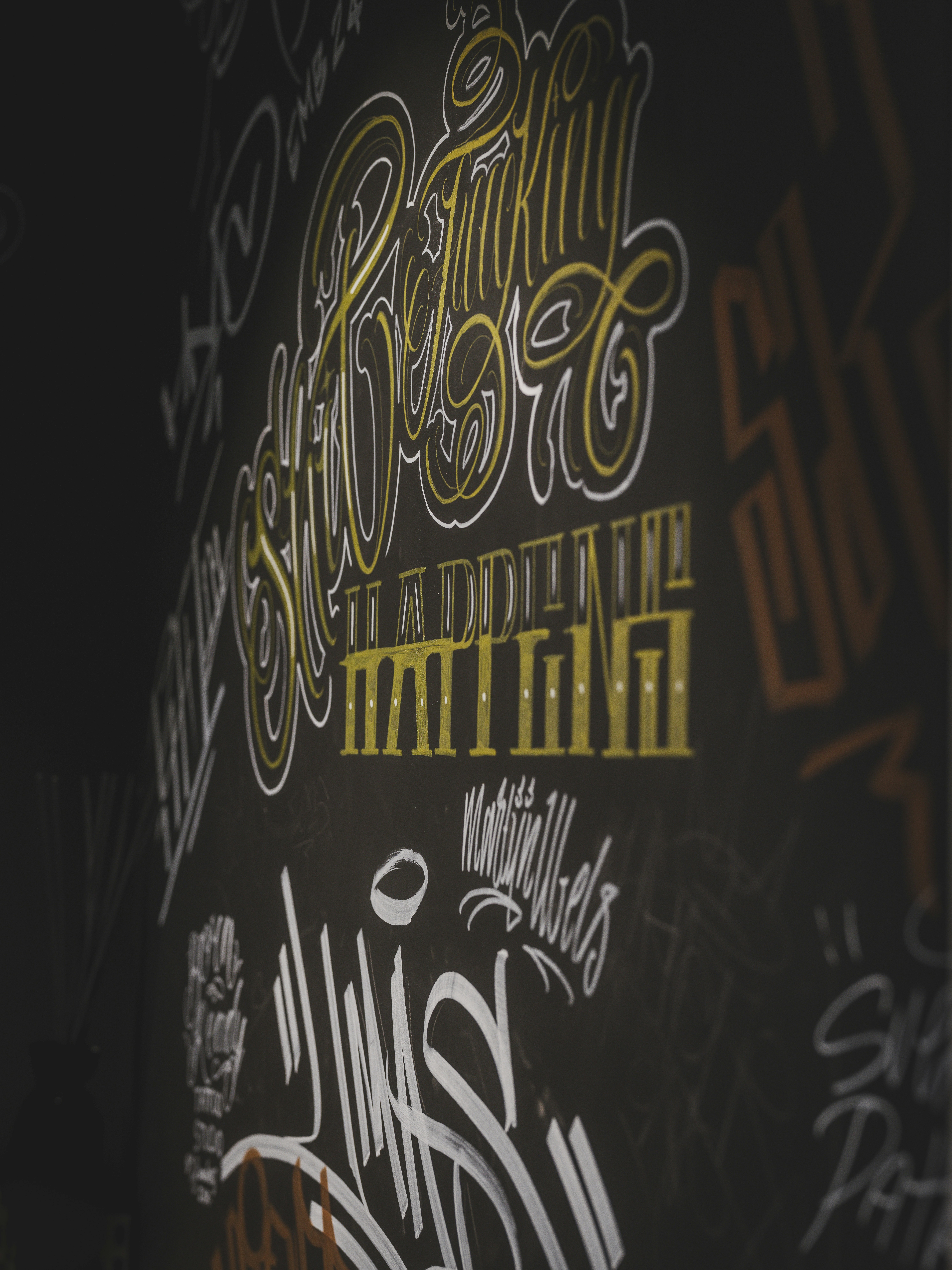 Graffiti-Kunst mit stilisierten Buchstaben an einer dunklen Wand.