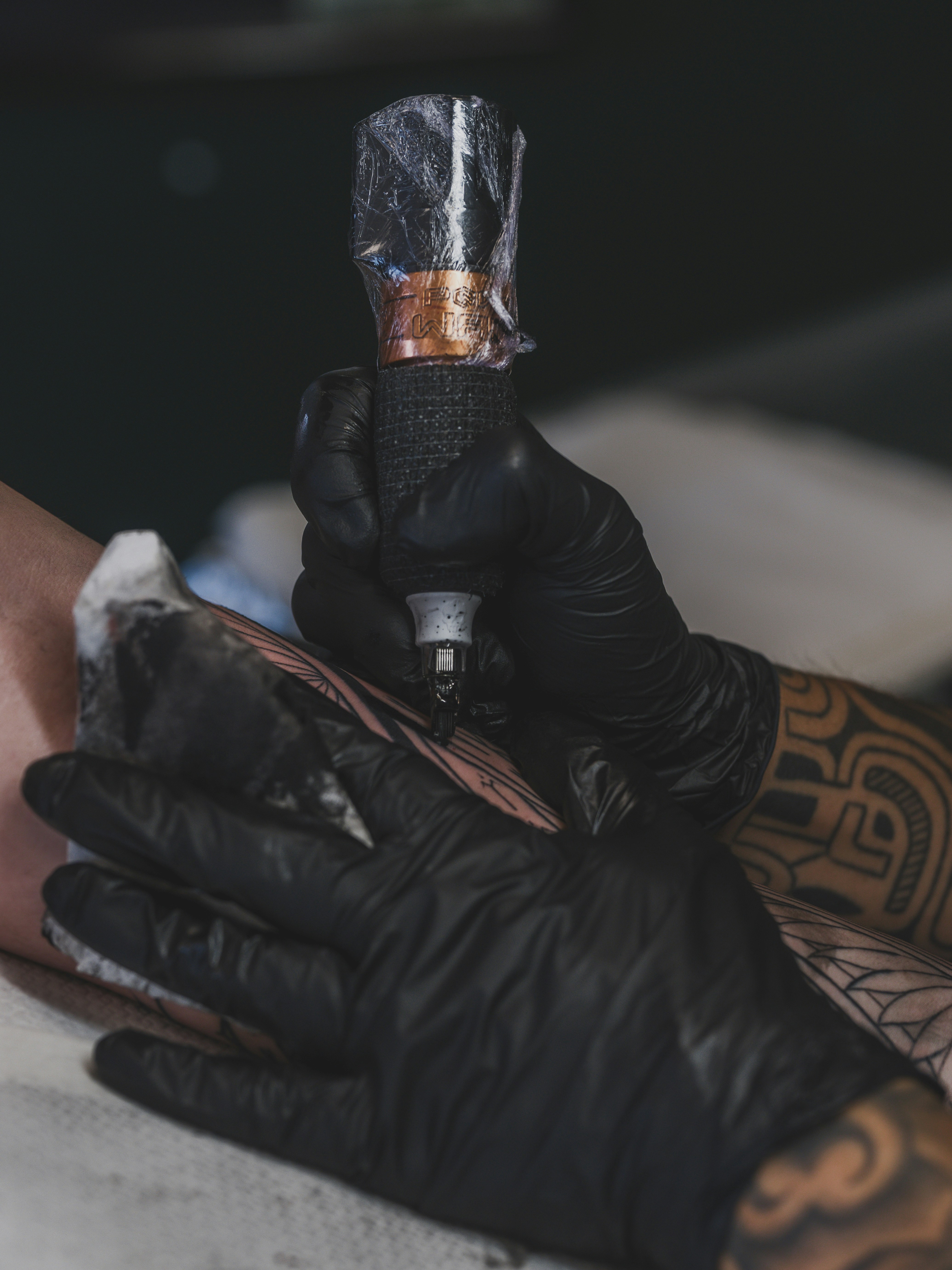 Artista tatuando um desenho no braço de uma pessoa.