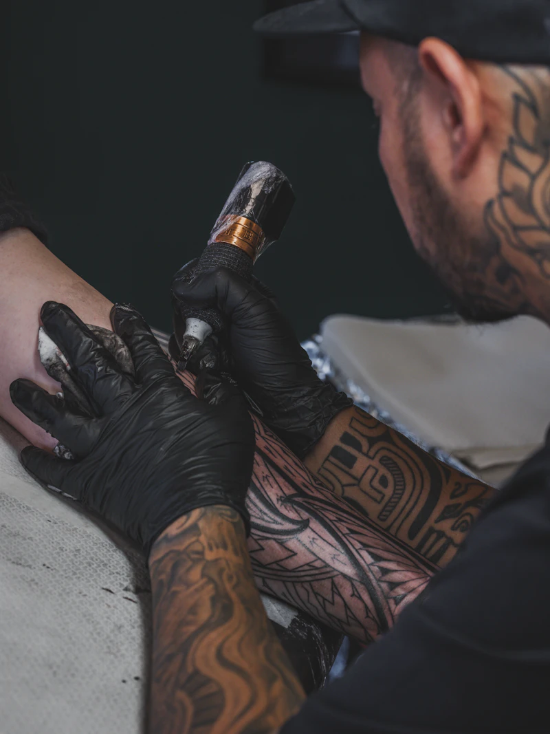 Tattoo artist working on a client's arm