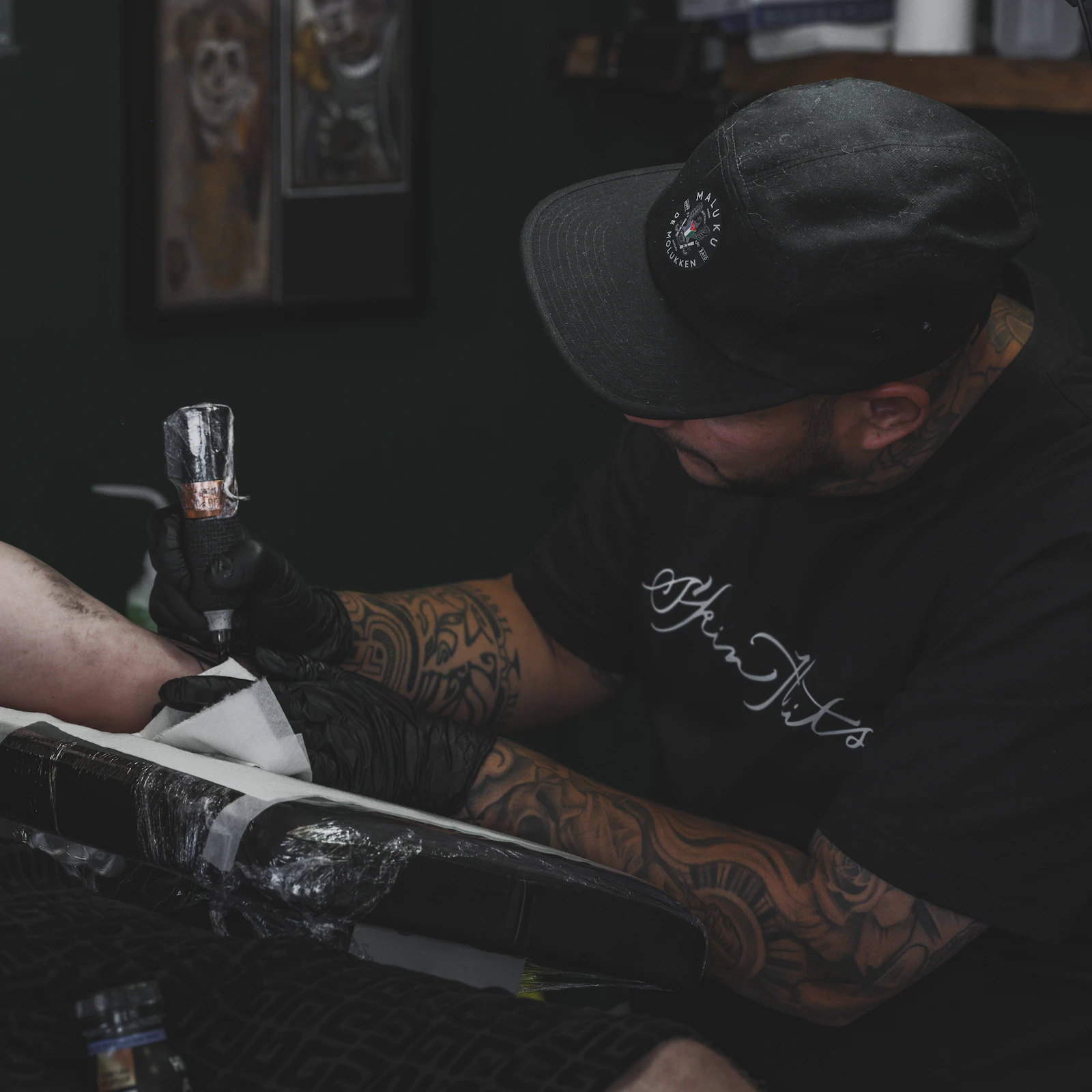 Tattoo artist working on a client's forearm in a studio