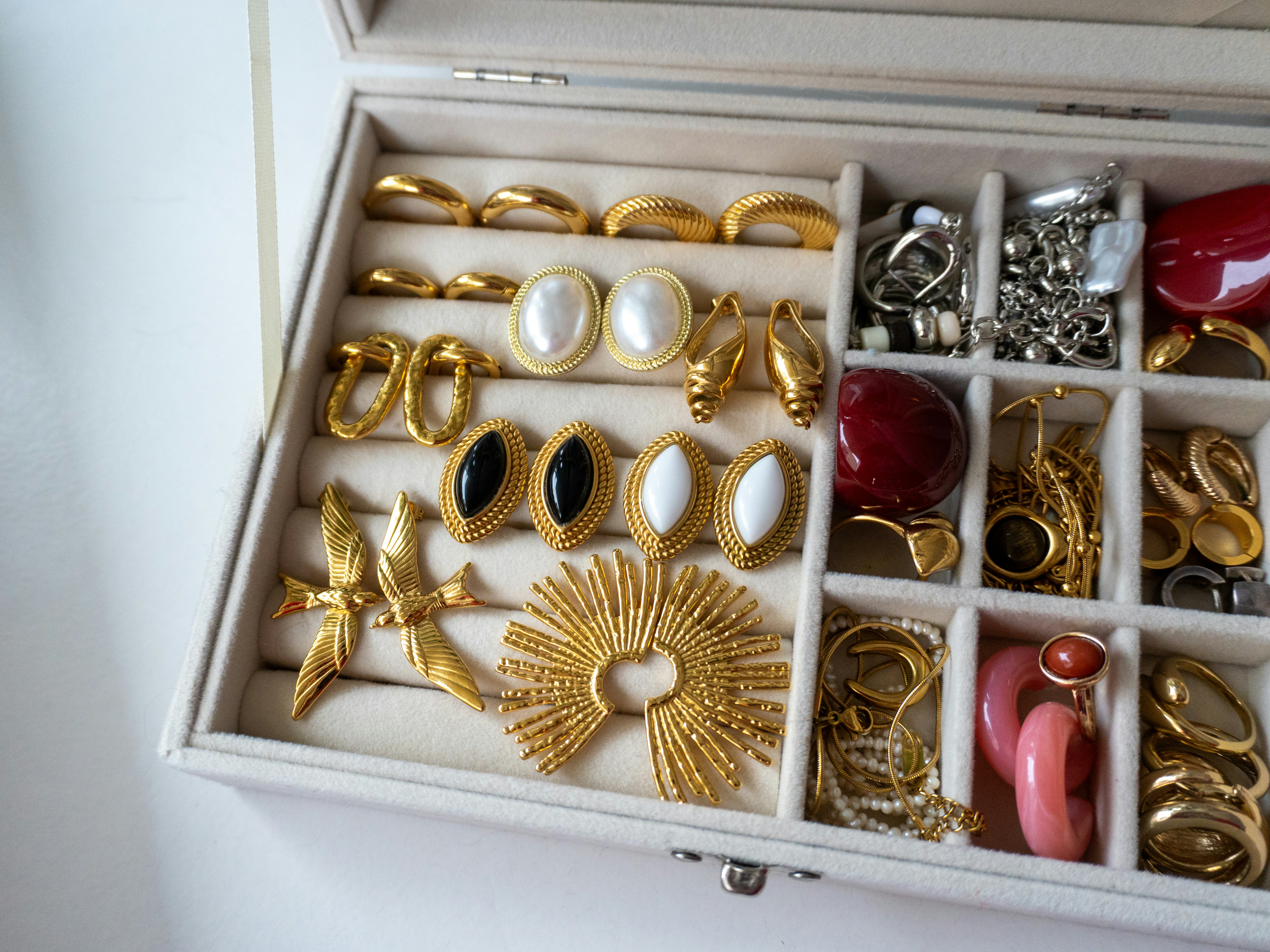 A jewelry box filled with assorted gold and pearl earrings.