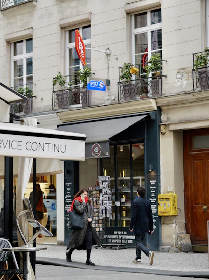 People walk past shops on a parisian street.