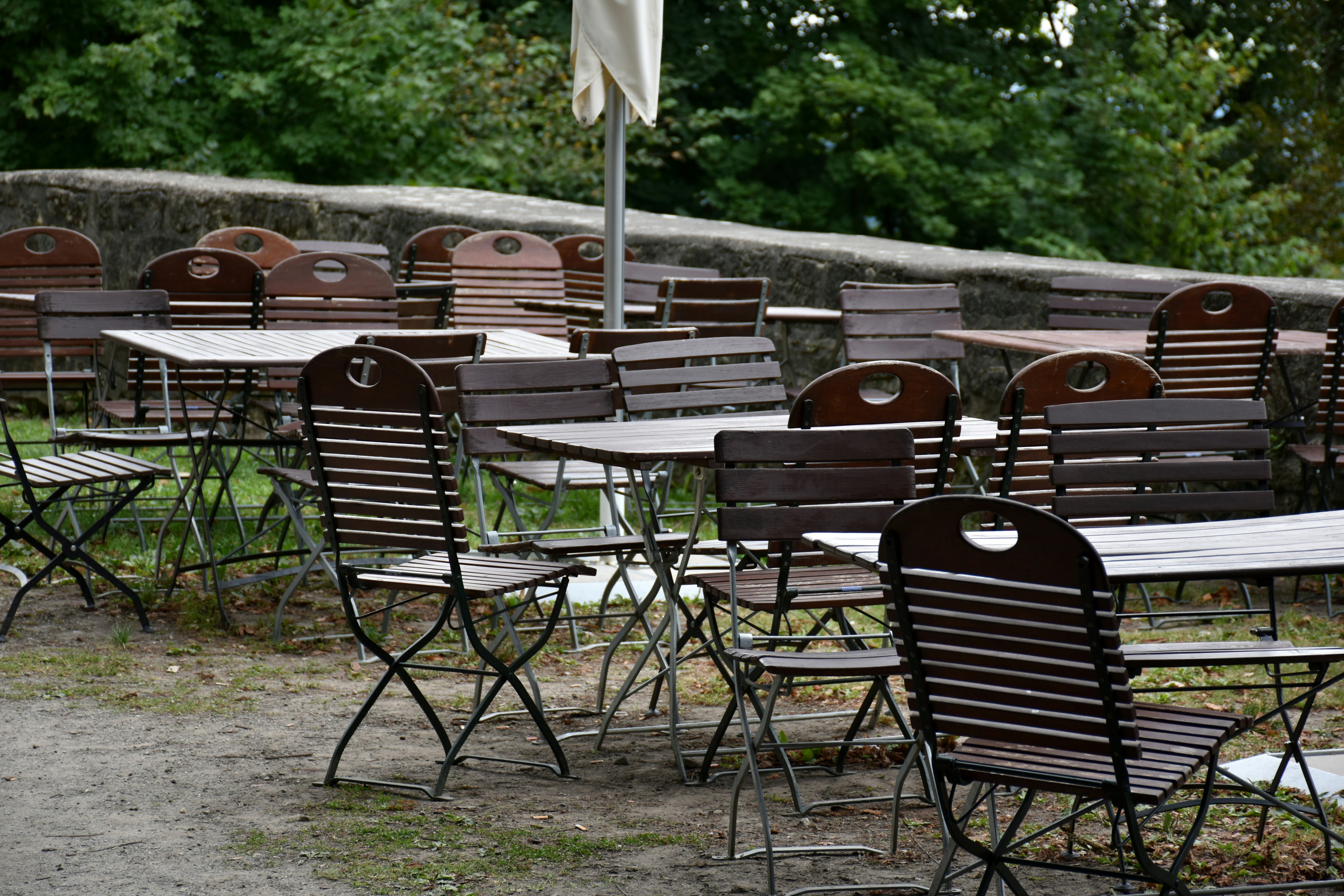 Empty outdoor cafe tables and chairs in a garden.