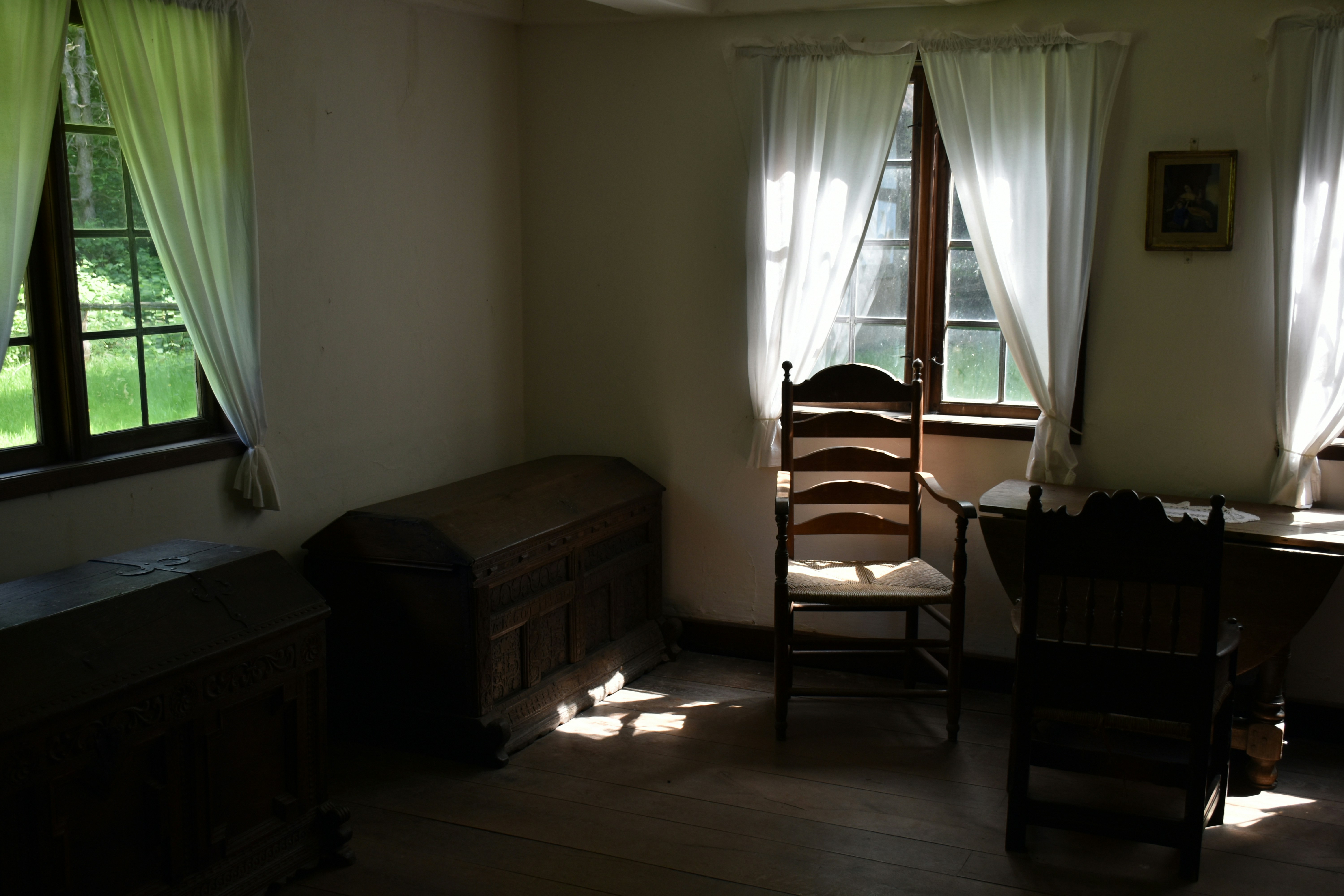 Sala de antigüedades con cofres y sillas de madera.