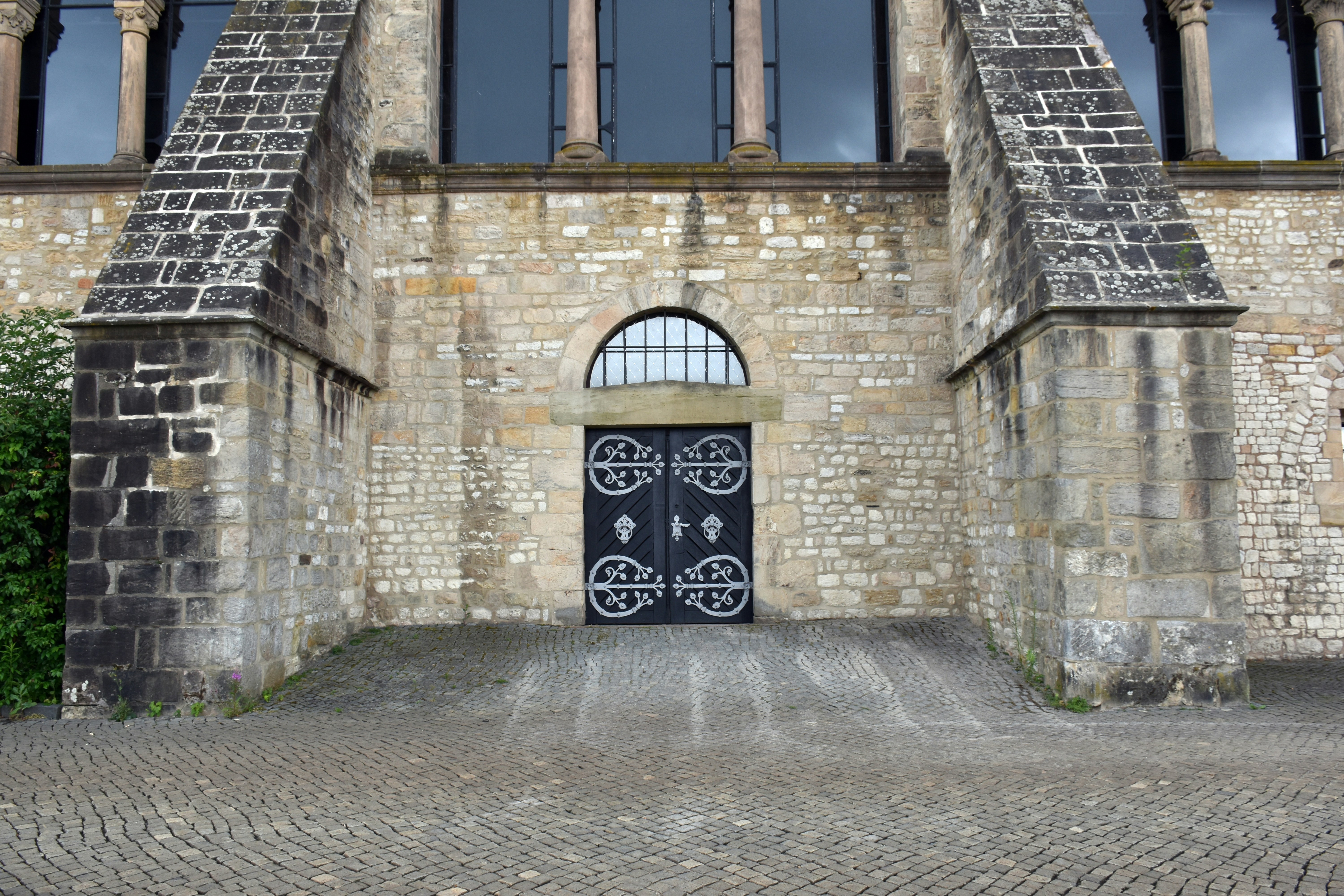 Puertas dobles negras ornamentadas encastadas en un edificio de piedra