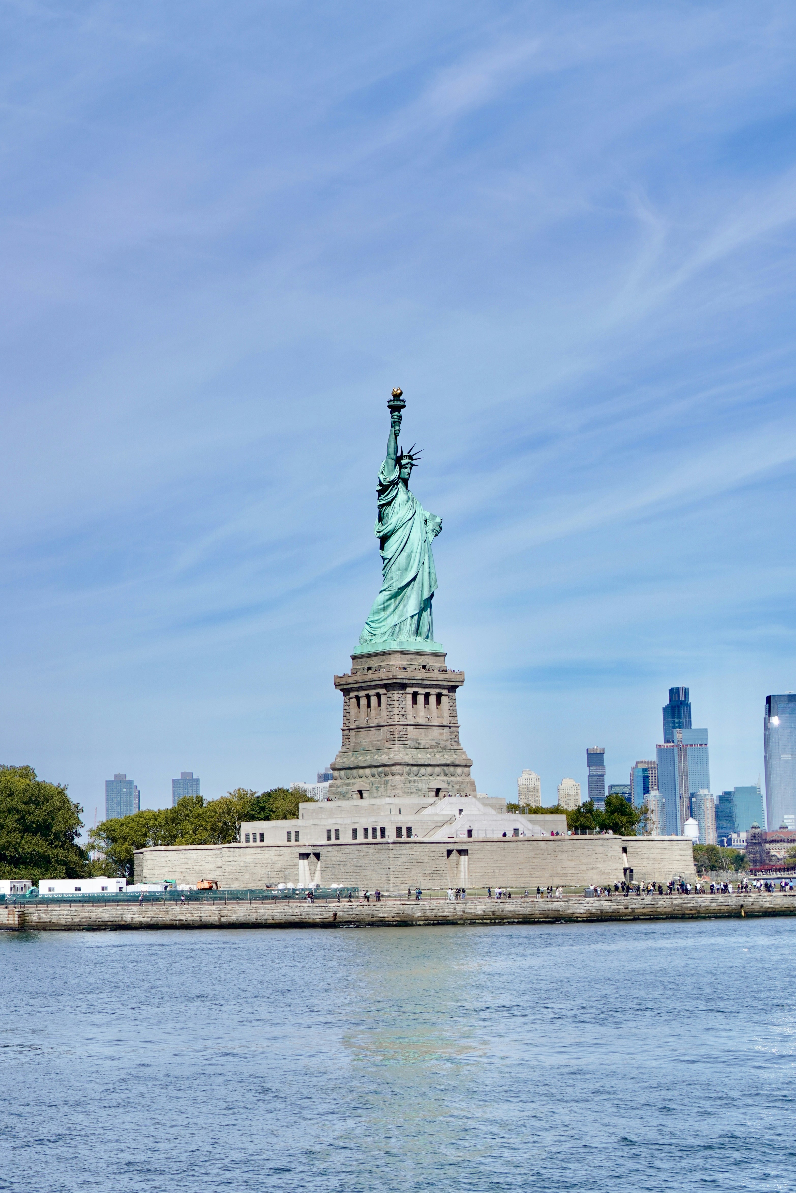 The statue of liberty stands tall against a blue sky.