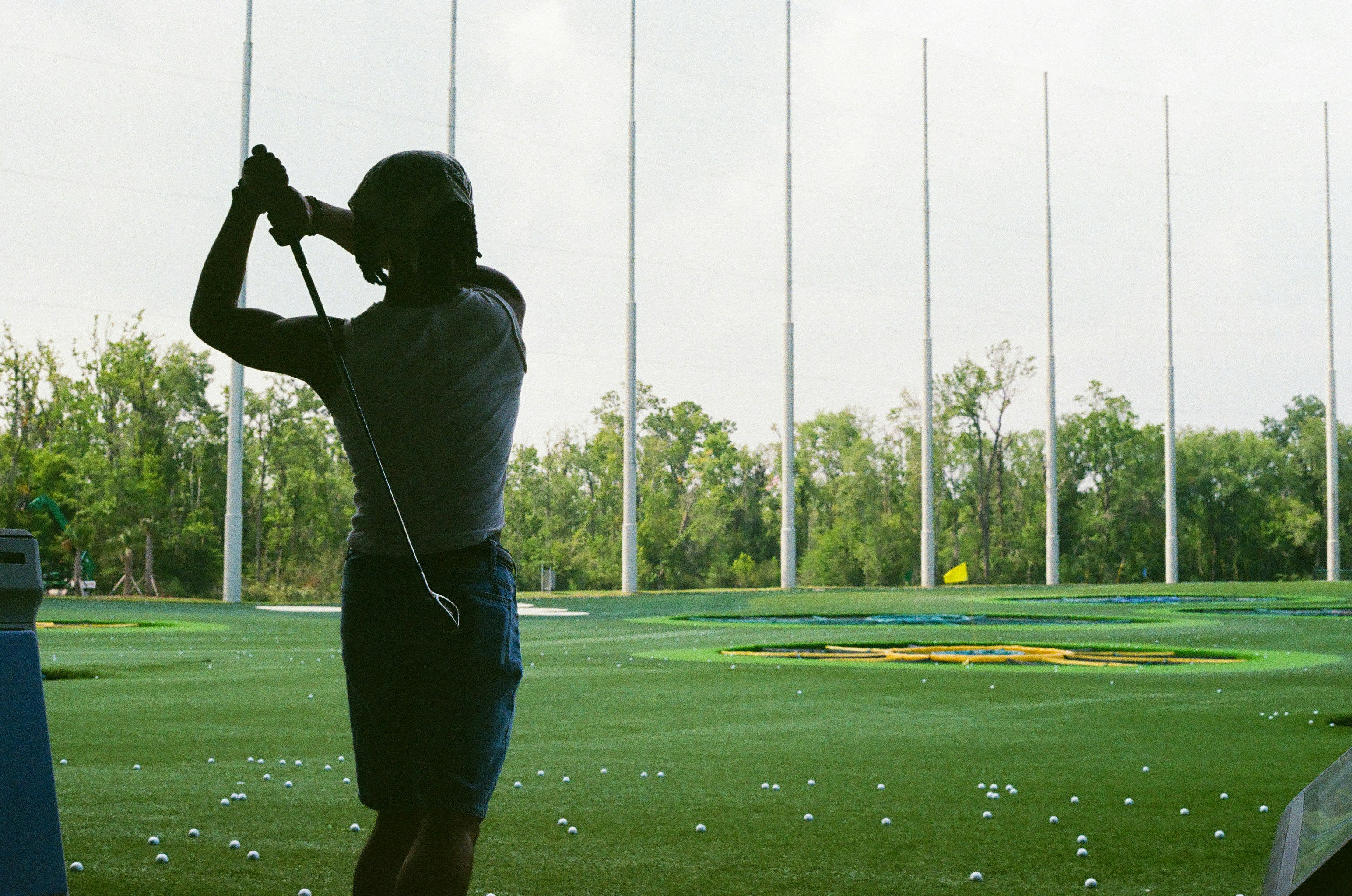 Person swinging golf club at driving range