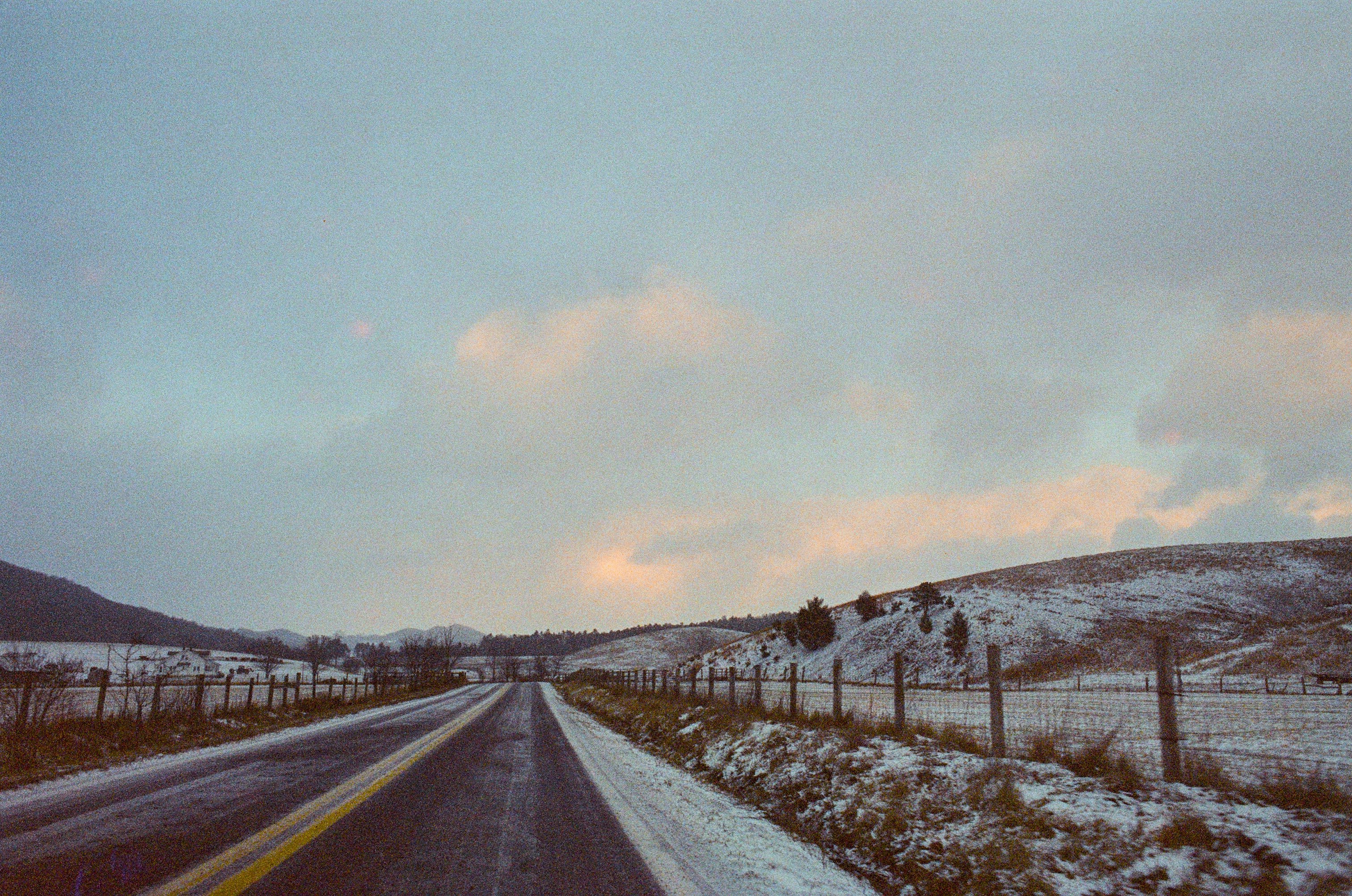 Wet road through a snowy landscape at dusk