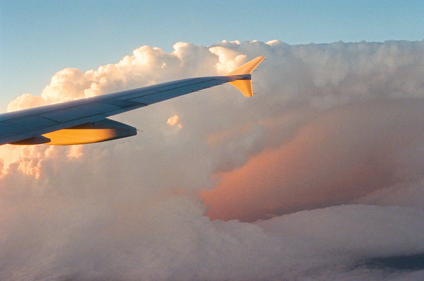 Jet wing over golden clouds at sunset
