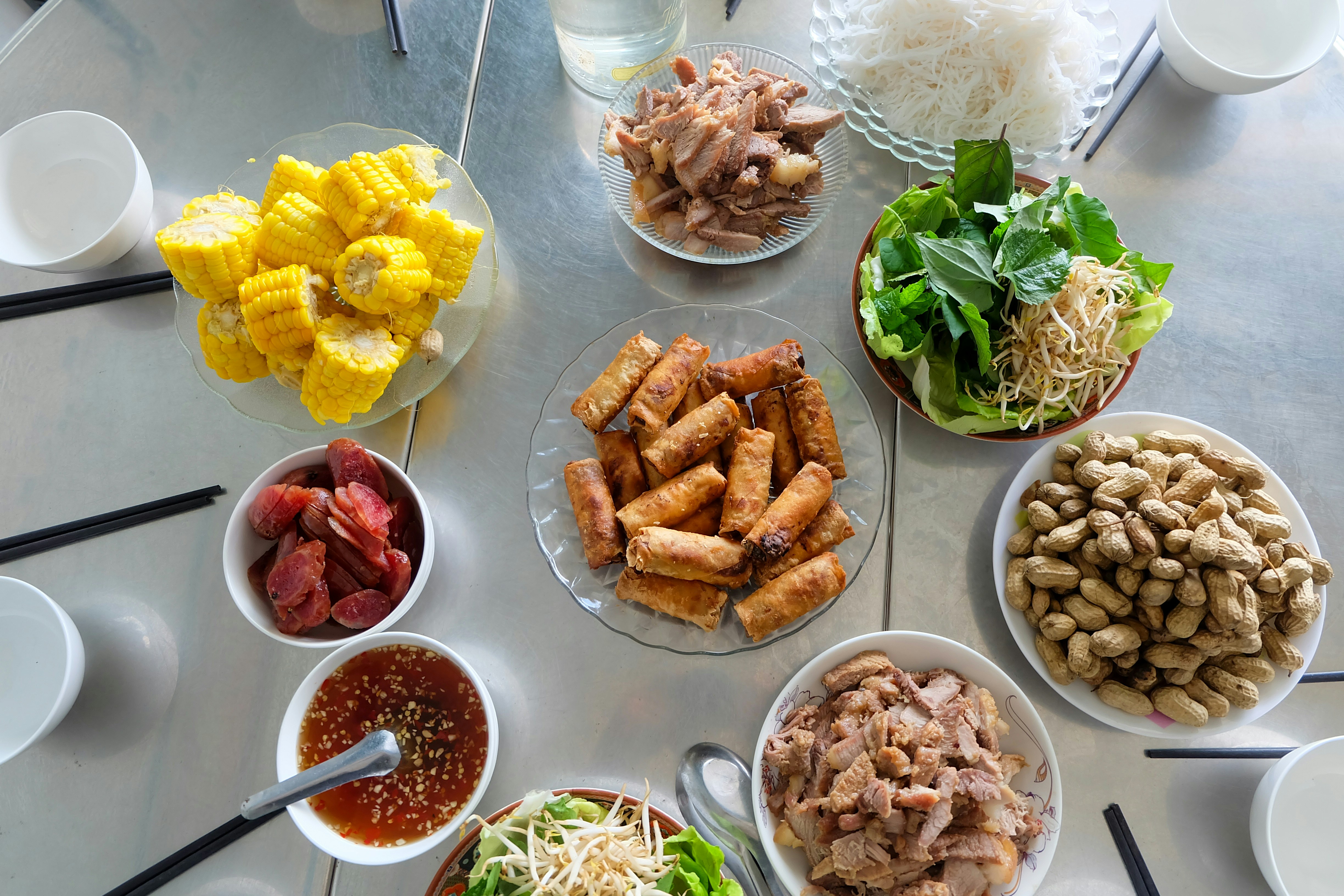A table filled with various vietnamese dishes and ingredients.