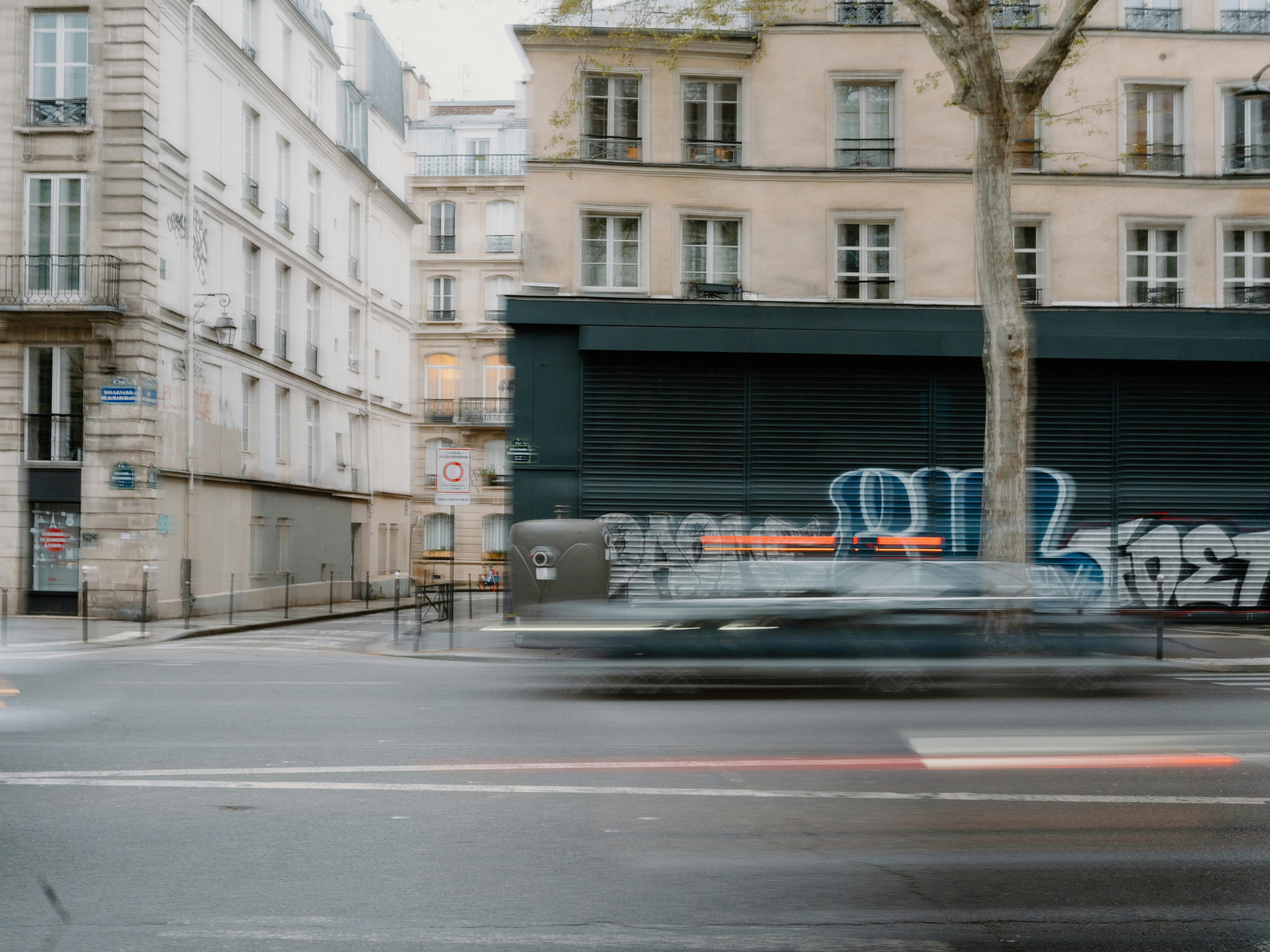 Blurry vehicle passes by graffiti-covered building.