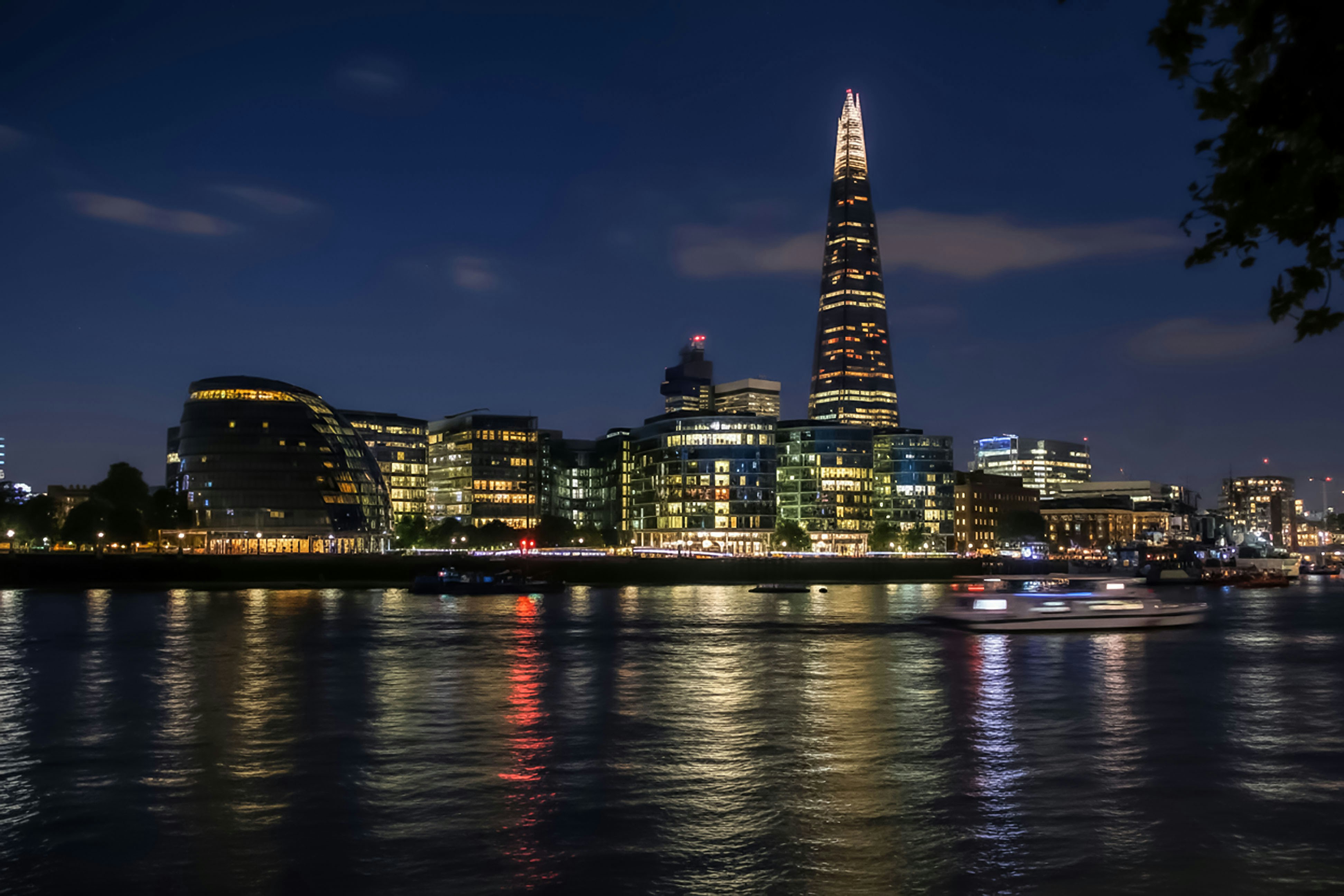 City skyline with illuminated buildings at night over river.