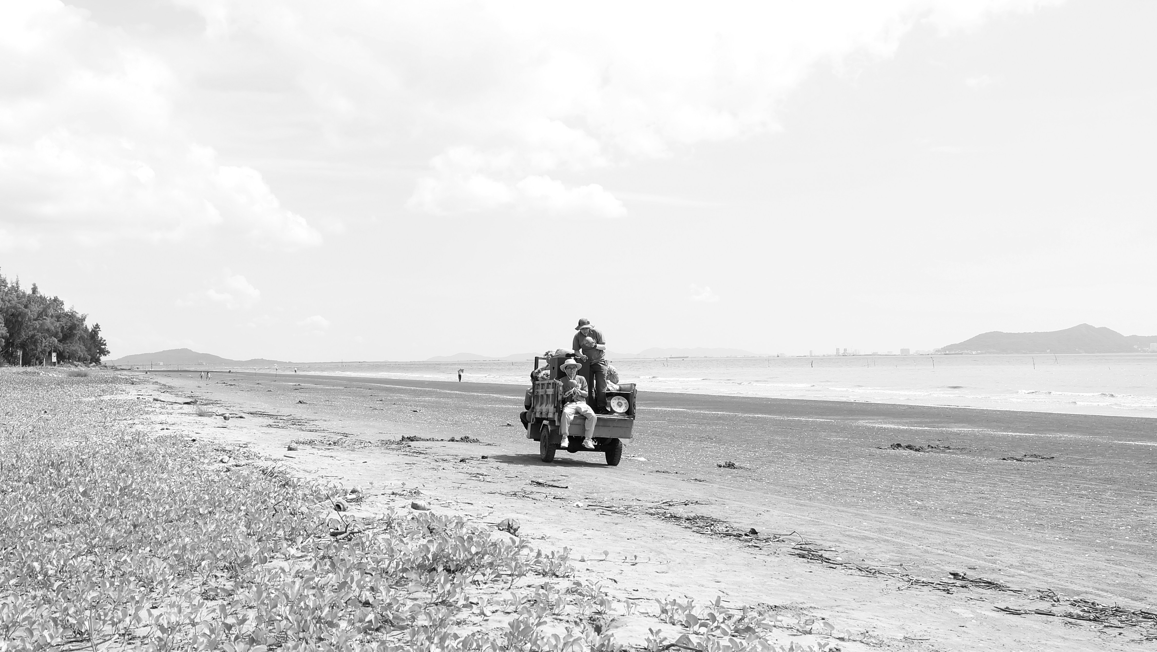 Two people ride a cart on a sandy beach.