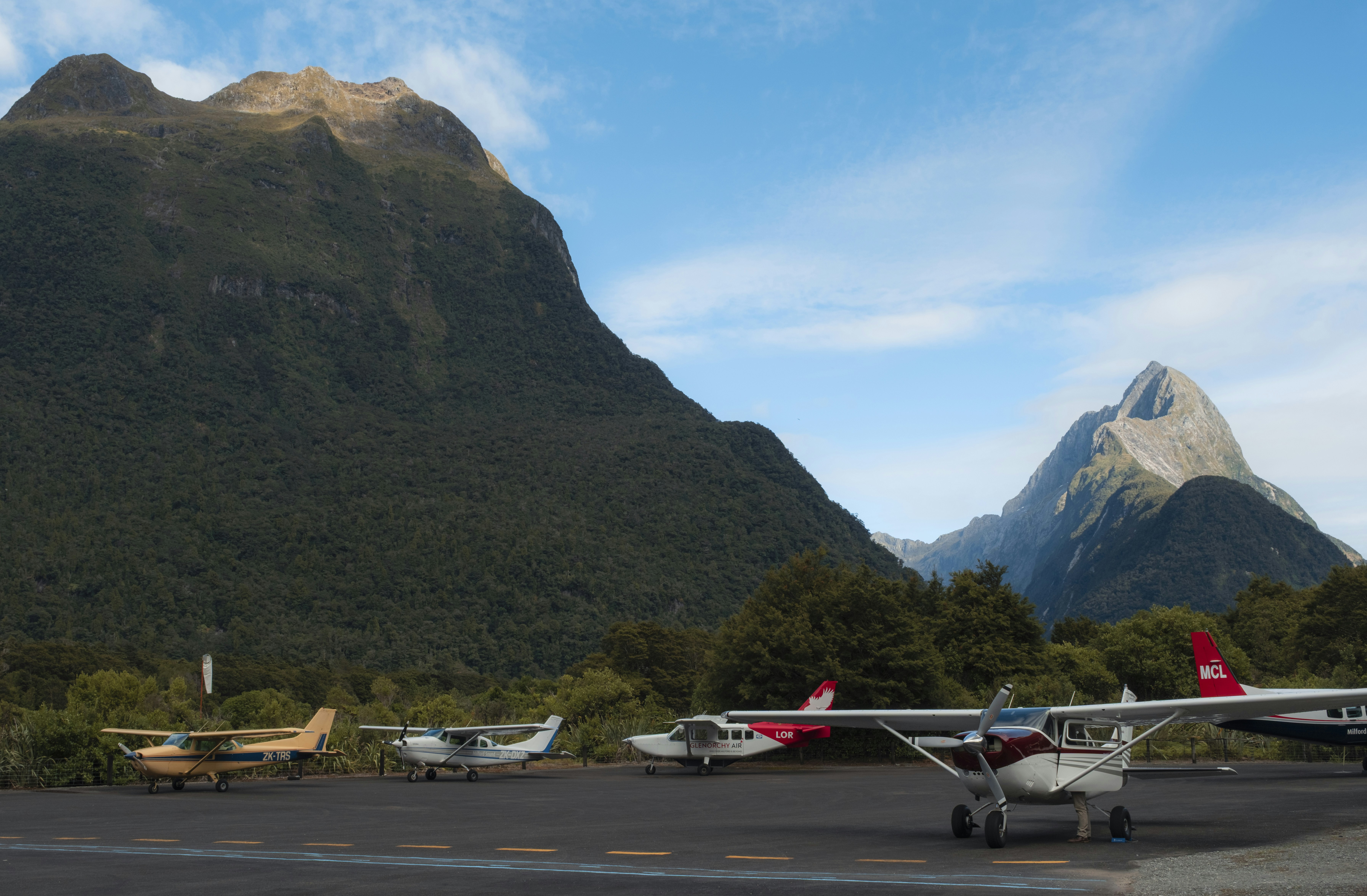 Small airplanes parked on tarmac with mountains behind