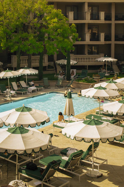 Resort pool with lounge chairs and umbrellas on sunny day.