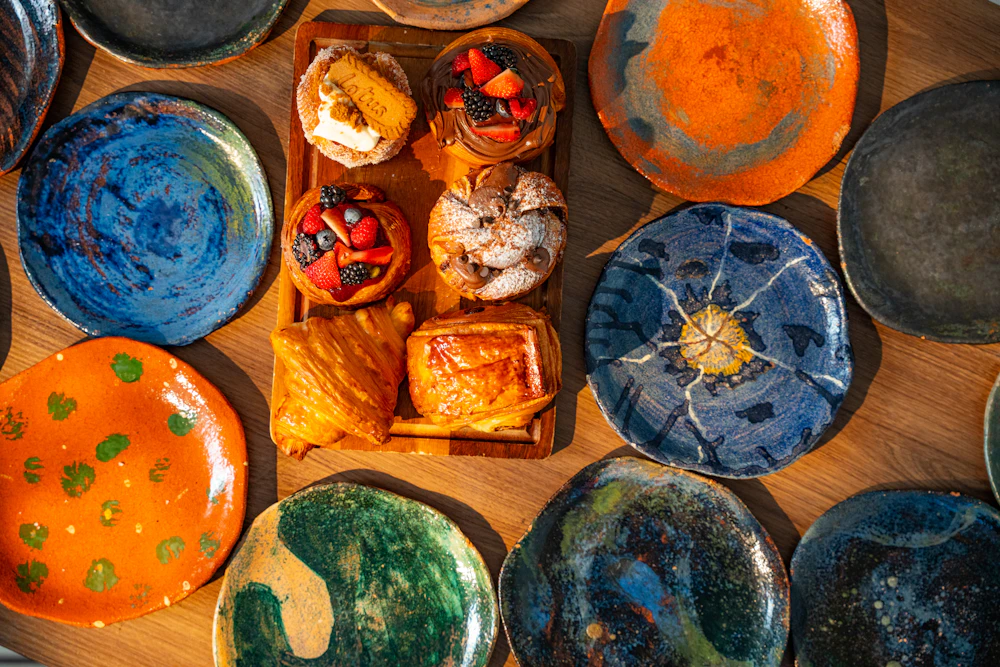 Artistic painted plates around assorted pastries and tarts