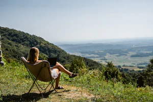 Mulher trabalhando no notebook com vista para um vale verde