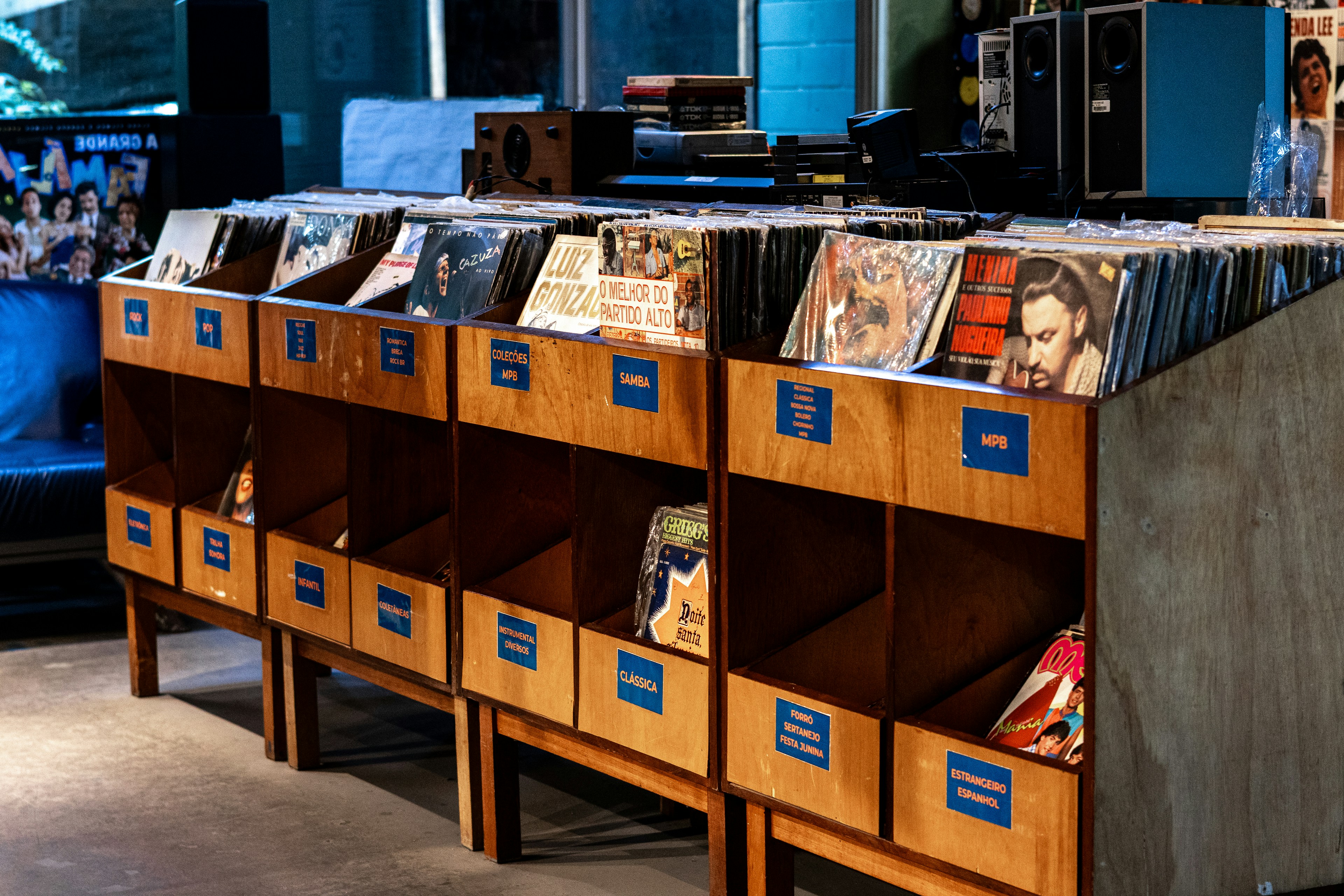 Rows of vinyl records are displayed in wooden crates, categorized by genre, inviting exploration.