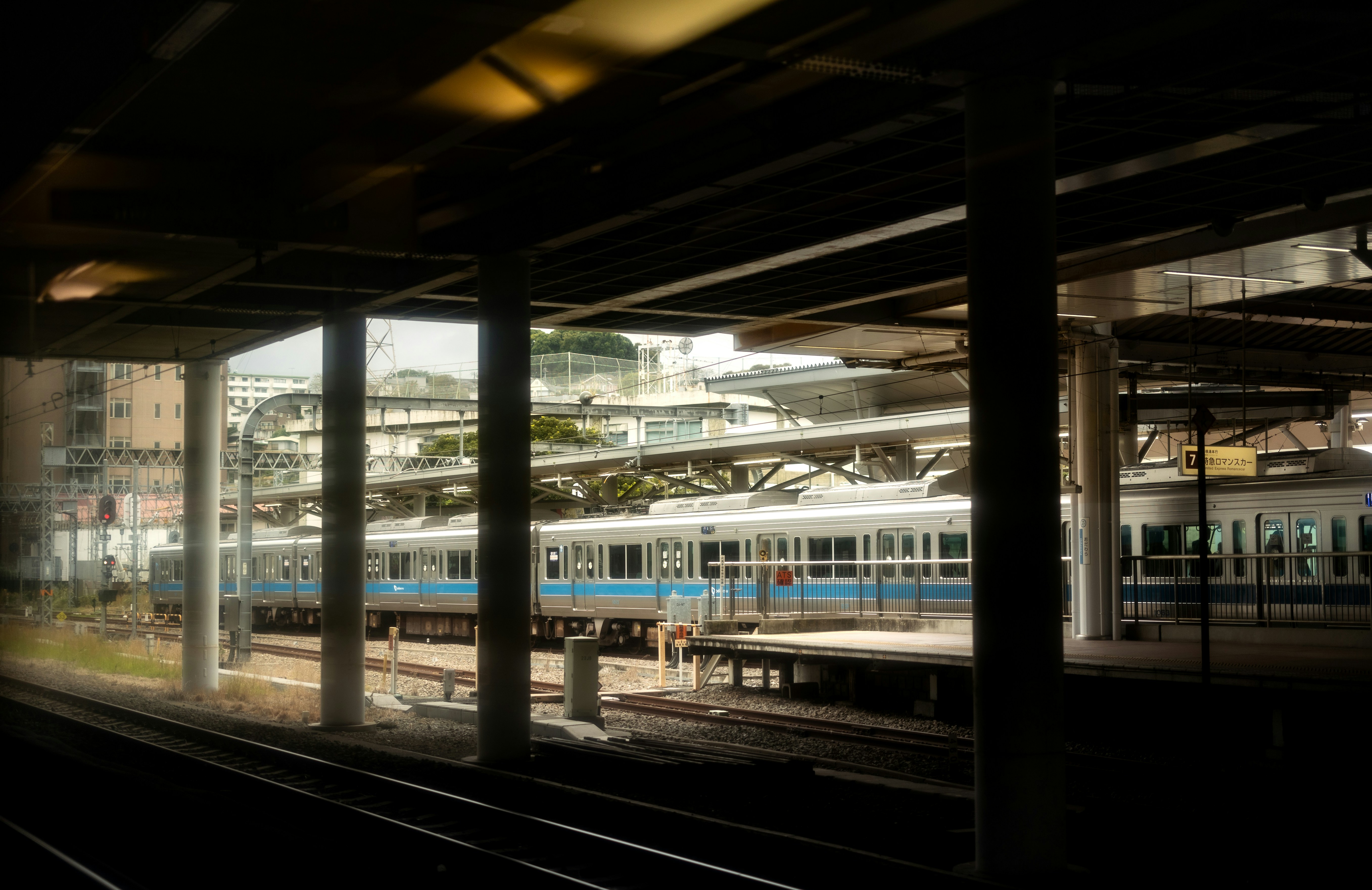 Trains at a station platform with buildings in background