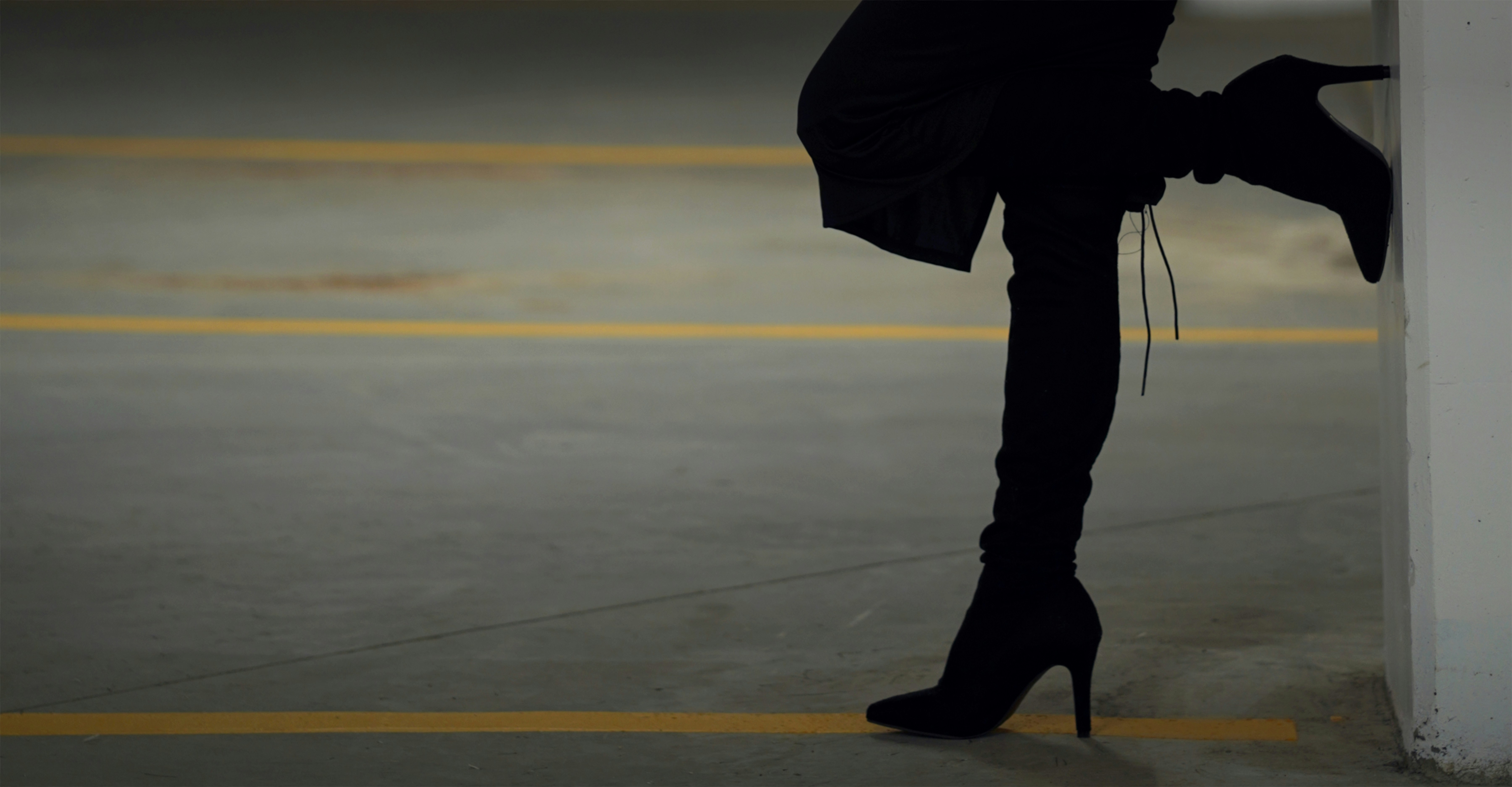 Donna con tacchi neri appoggiata al muro